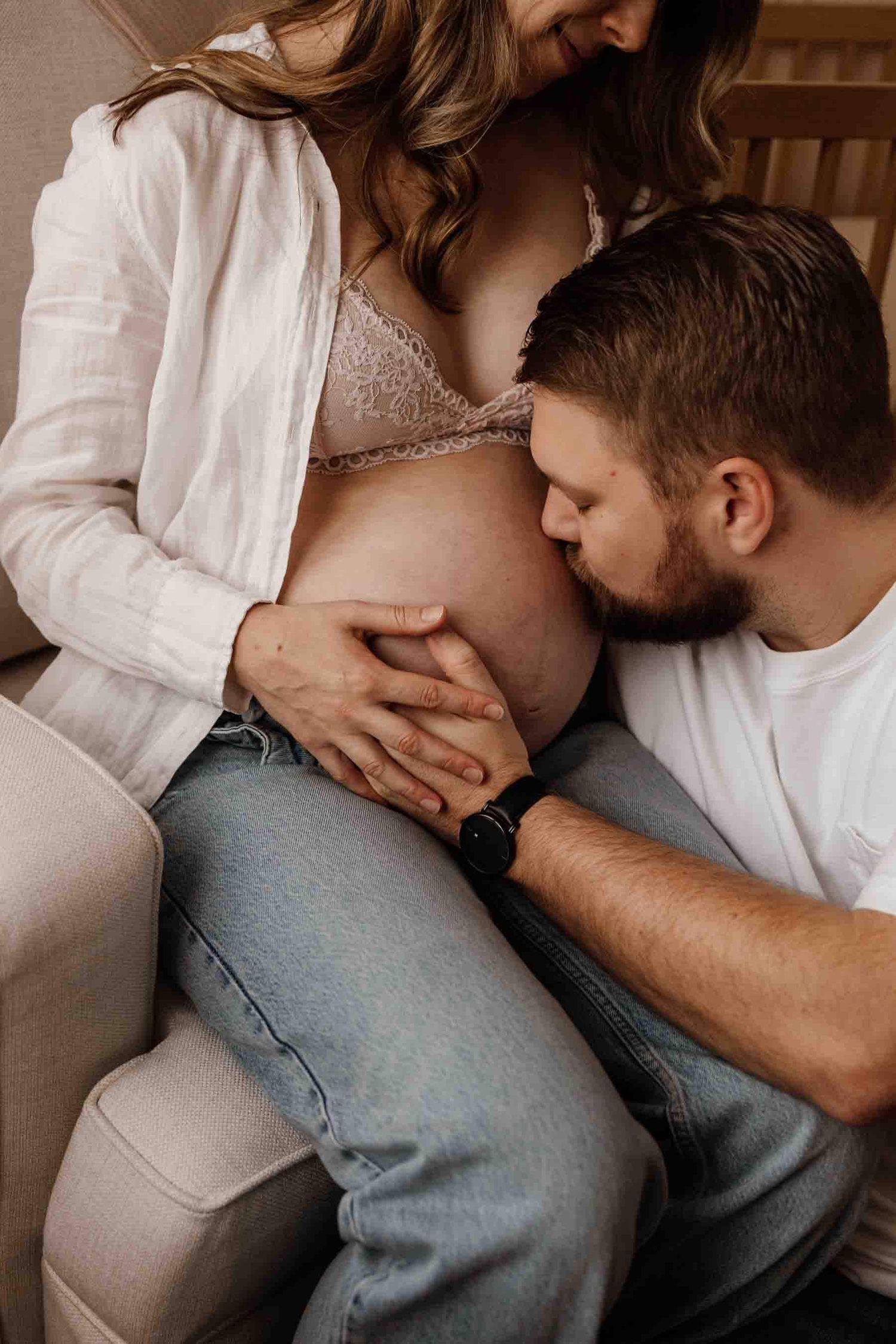 Father kissing mom's baby bump during a natural lifestyle maternity photography session in Toronto.