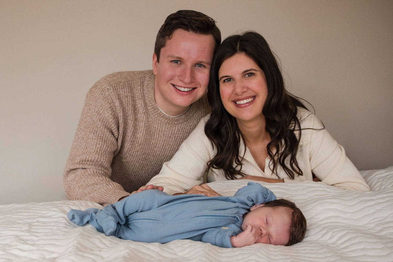 New parents posing with their sleeping newborn during a lifestyle newborn photography session in Toronto.
