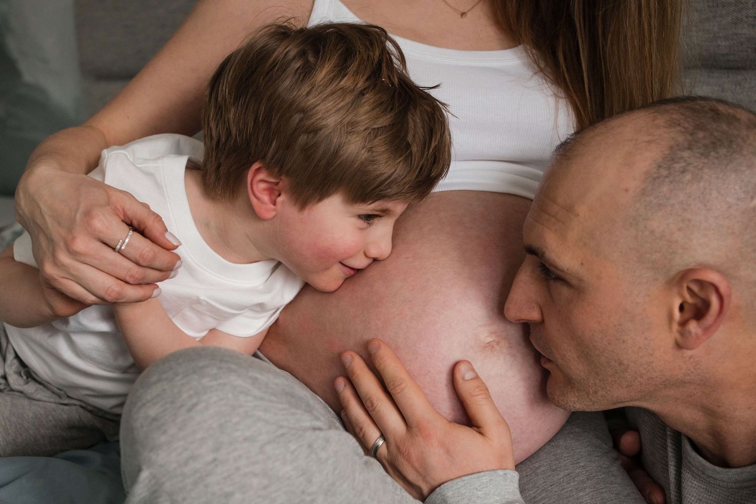 Parents and big brother sharing a sweet moment with baby on the way during an in-home maternity photography session in Toronto.