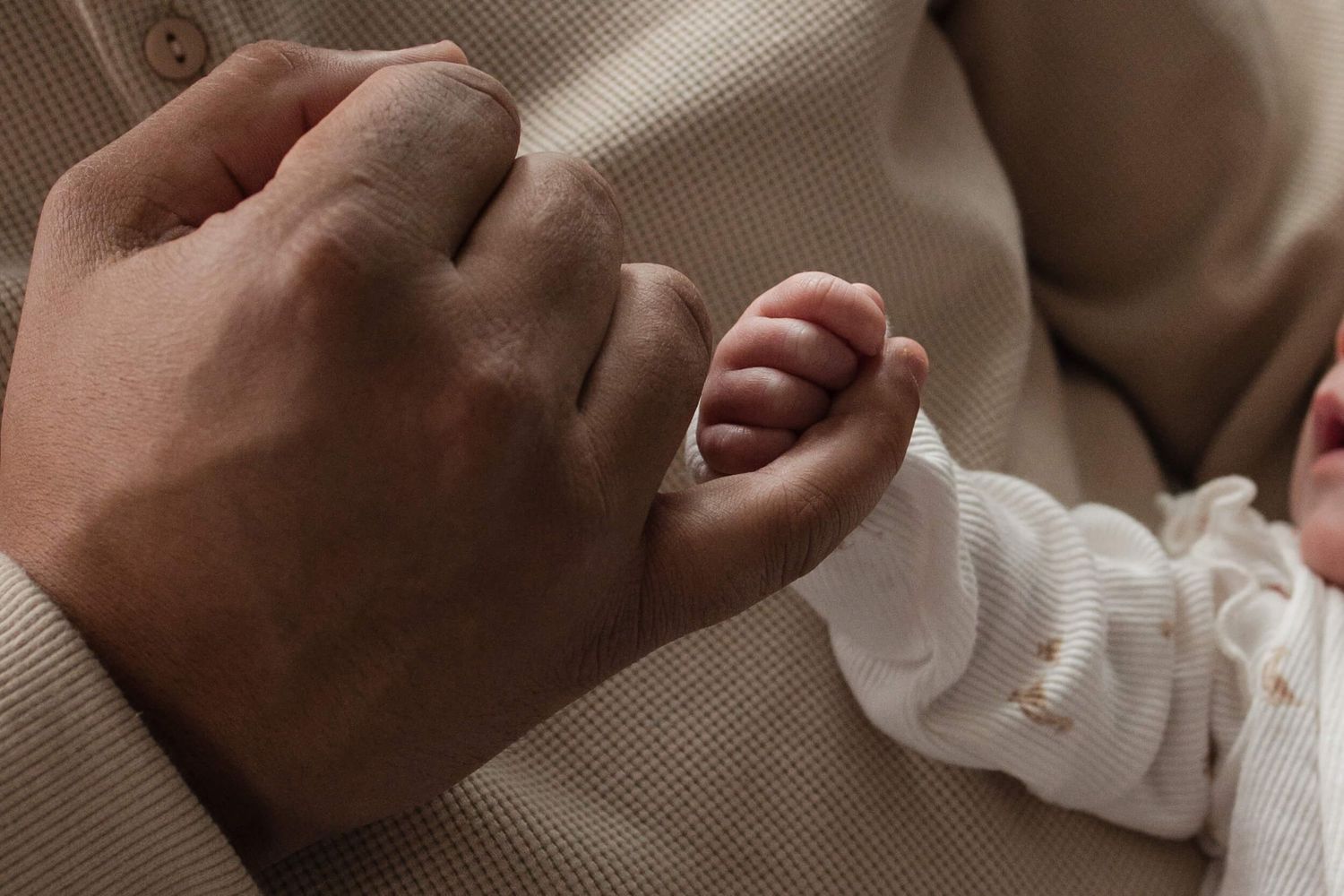 Tiny newborn fingers wrapped around a parent’s hand during an in-home newborn photography session in Toronto, capturing love and connection.