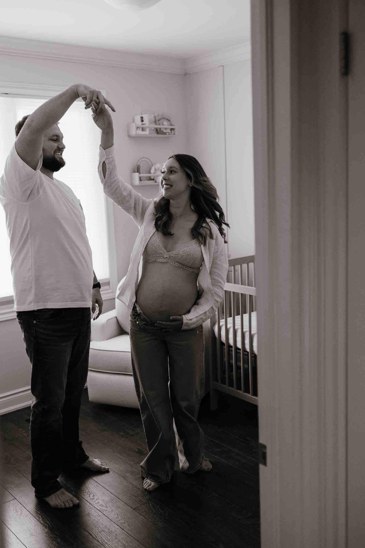 Expectant parents sharing a joyful moment in their baby's nursery during an in-home maternity photography session in Toronto.
