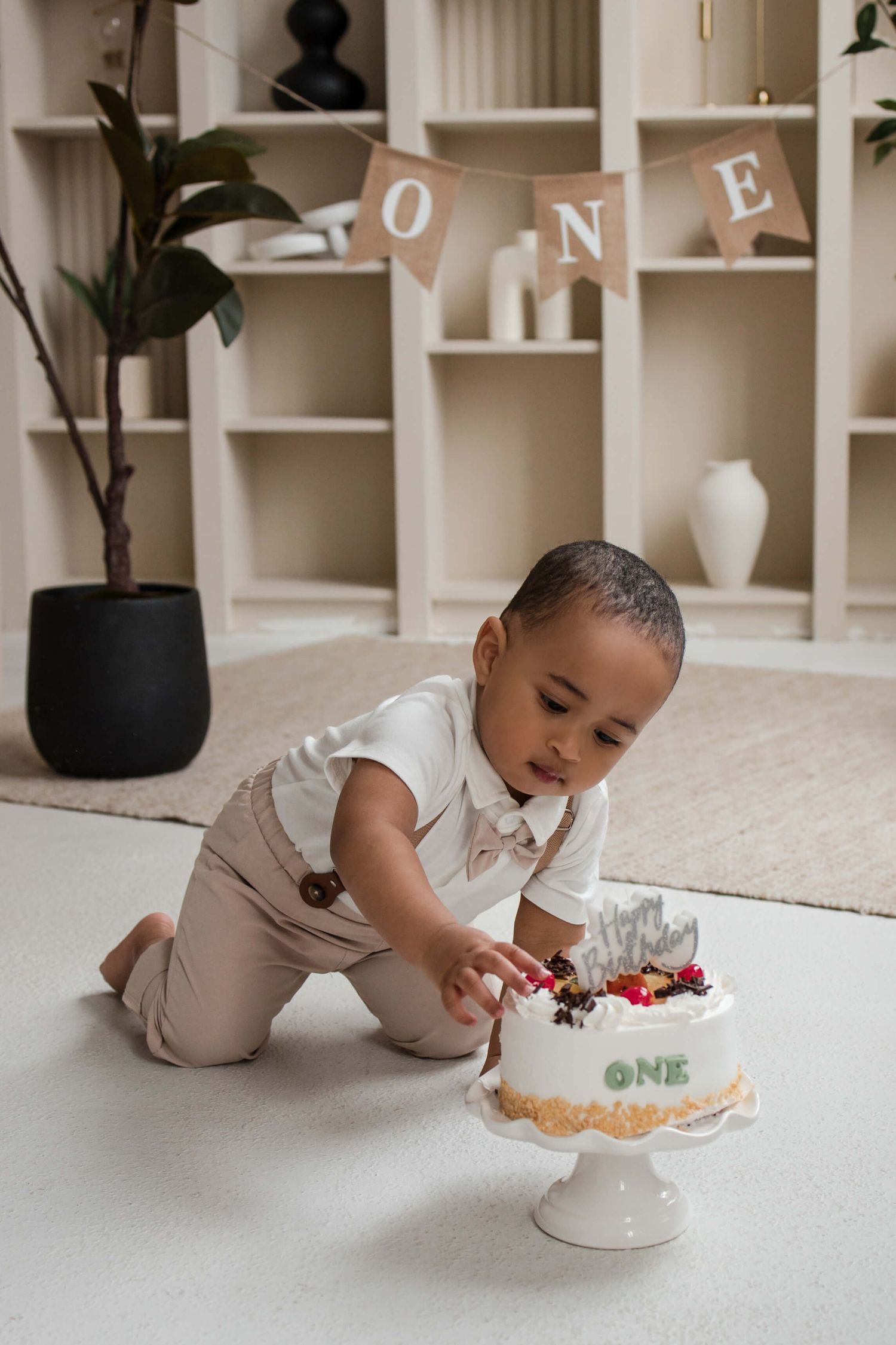 One-year-old enjoying a cake smash session at Mint Room Studios in Toronto with a simple neutral setup, timeless decor, and natural style.