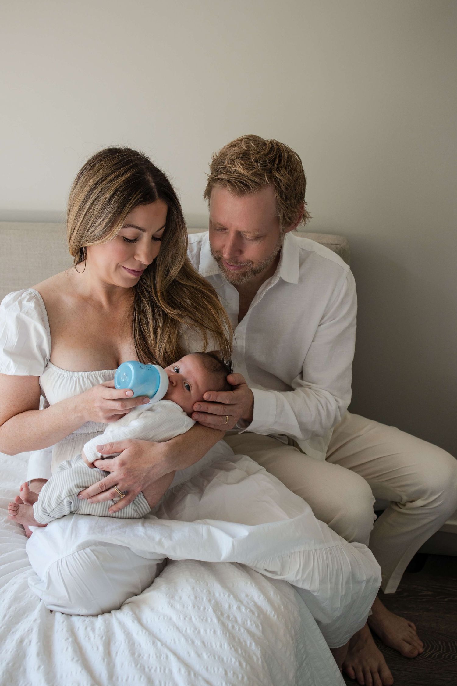 Mother feeding newborn while dad stays close during a lifestyle newborn photography session in Toronto.