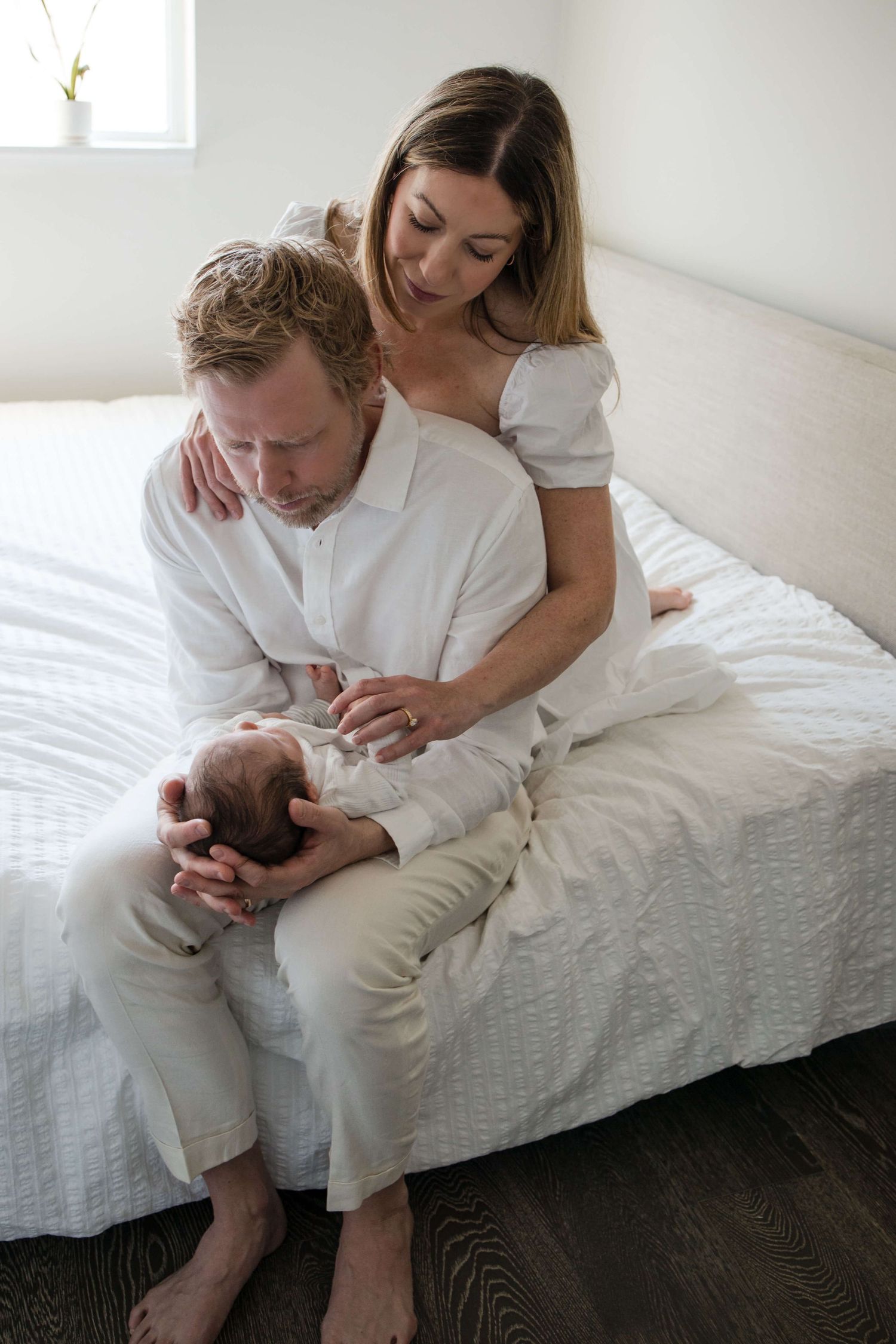 Mother and father sharing a quiet moment with their newborn during a lifestyle newborn session in Toronto.