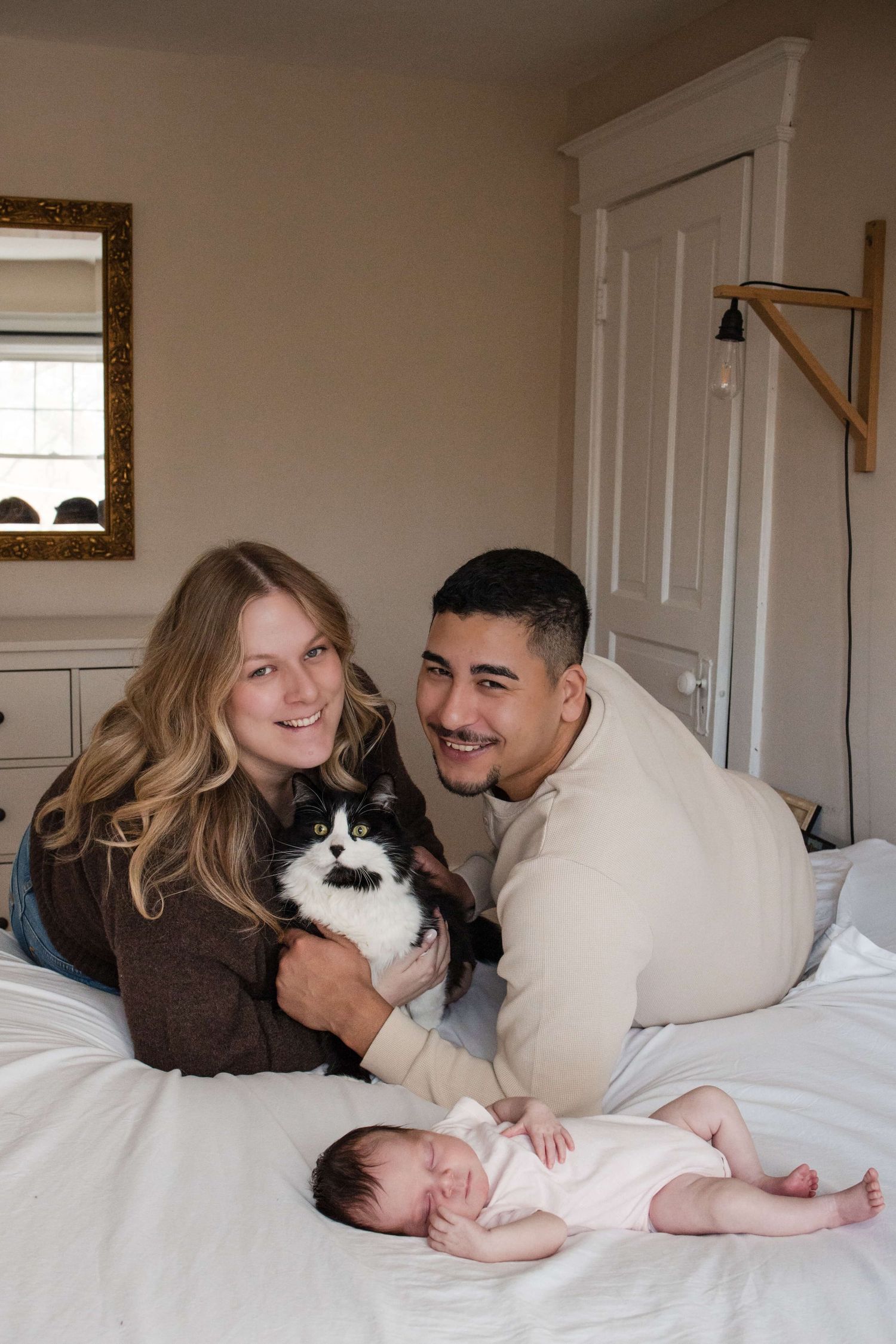 Parents, newborn, and family cat together during an in-home newborn photography session in Toronto, capturing authentic family life.