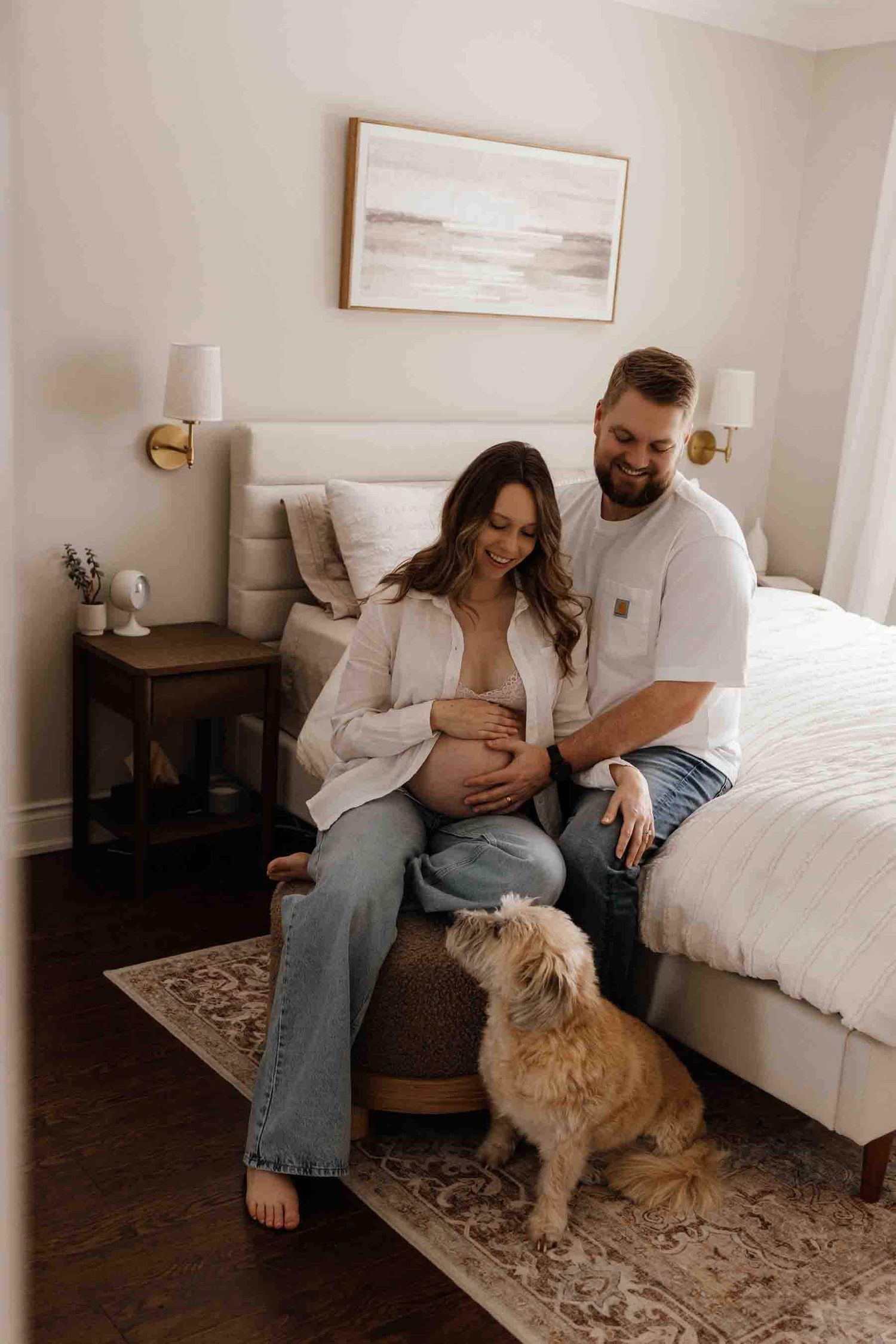 Expectant parents sharing a quiet moment with their dog during an in-home maternity photography session in Toronto.