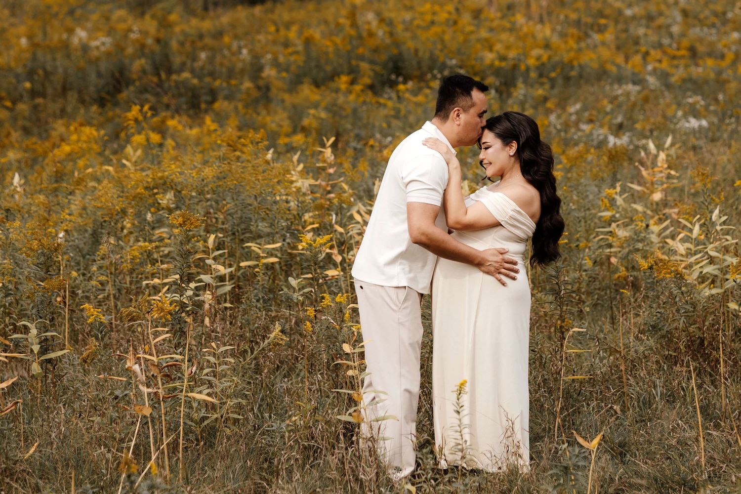Expectant parents sharing a tender moment during an  autumn outdoor maternity photography session at Evergreen Brick Works in Toronto.