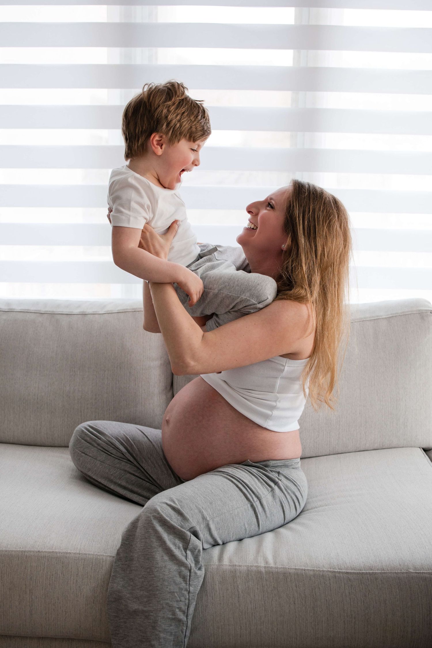Expectant mother lifting her child during an in-home maternity photography session in Toronto, celebrating motherhood and family.
