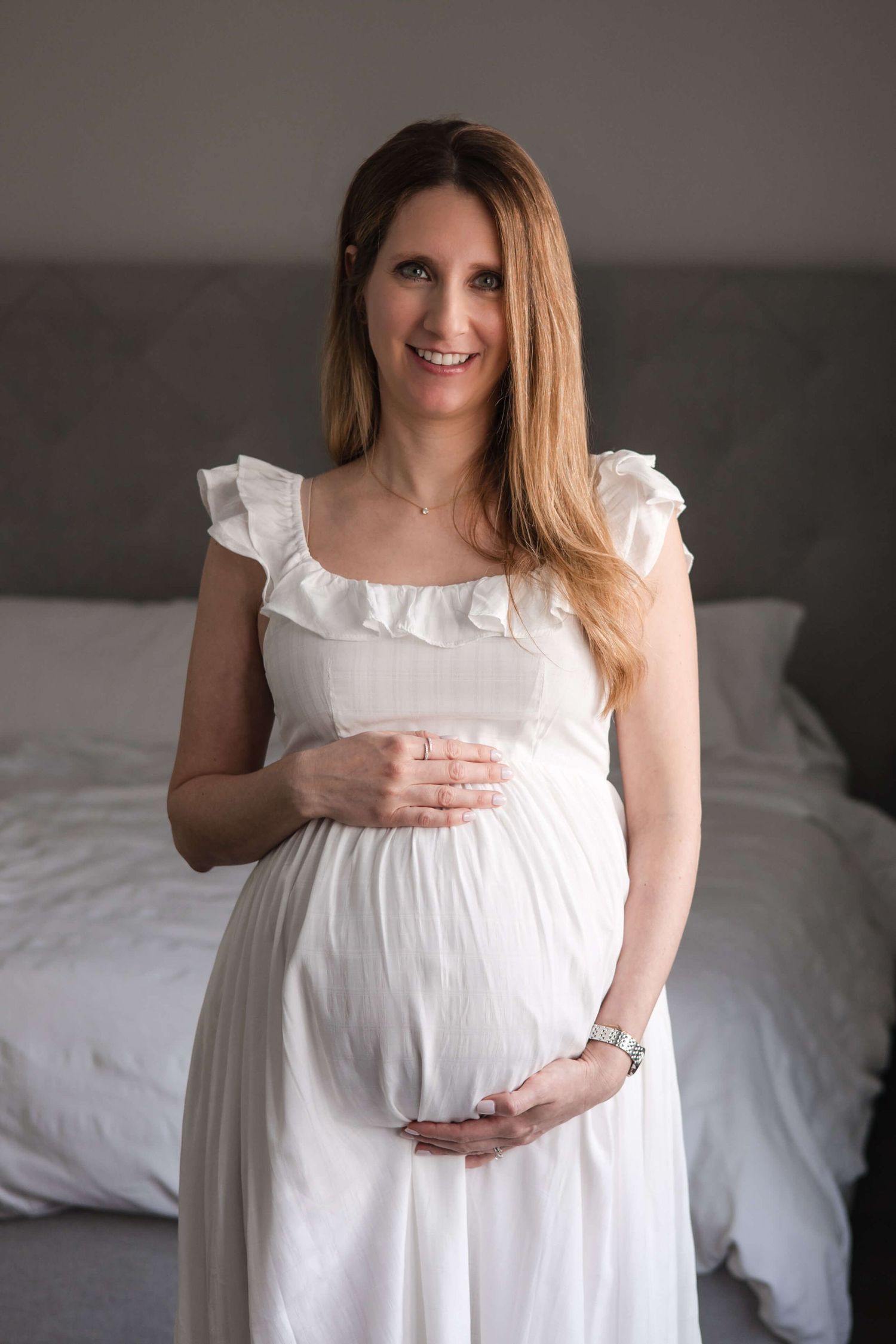 Expectant mother holding her baby bump during an in-home maternity photography session in Toronto, celebrating motherhood and new beginnings