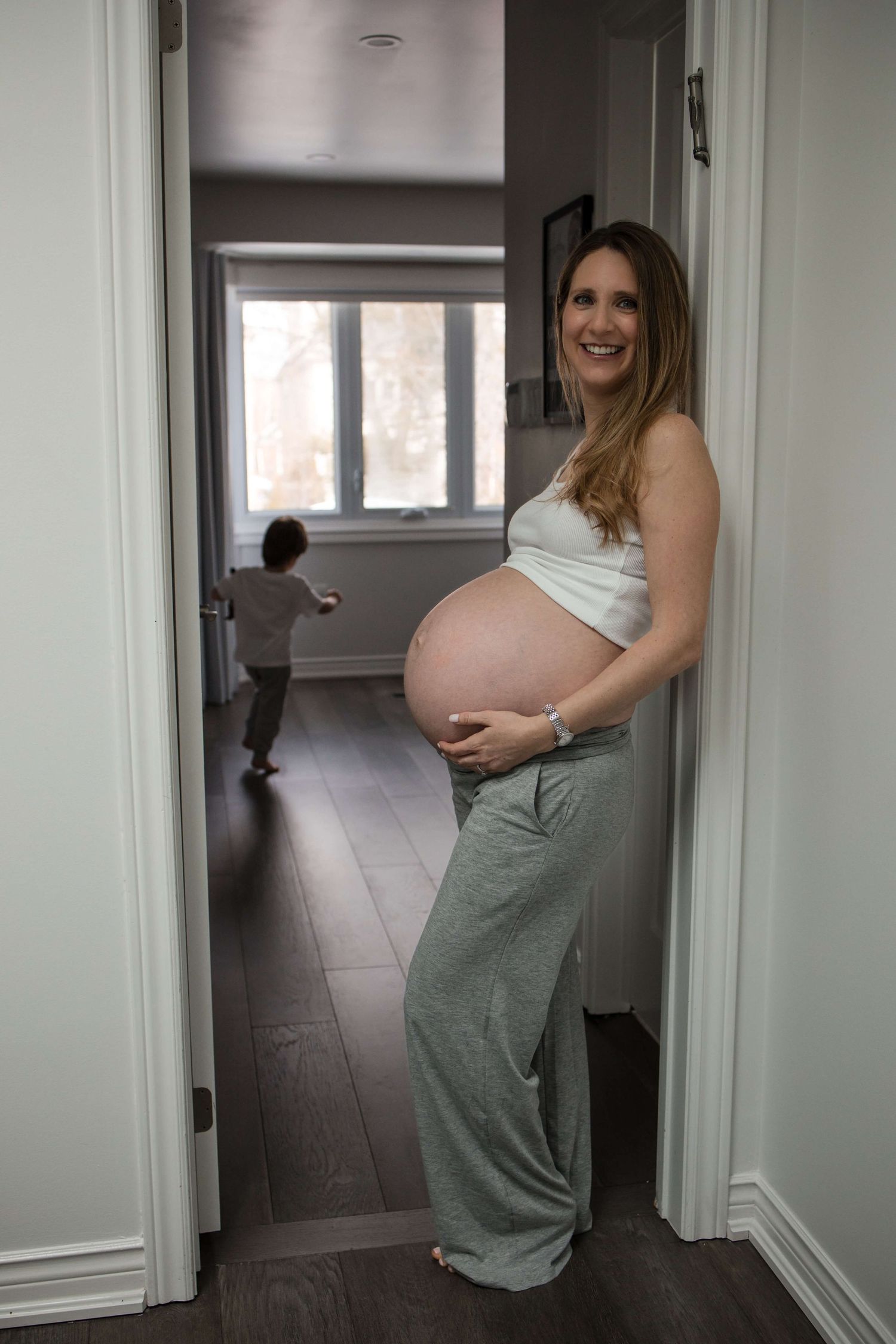 Expectant mother embracing her baby bump at home during a maternity photography session in Toronto, celebrating motherhood and anticipation.
