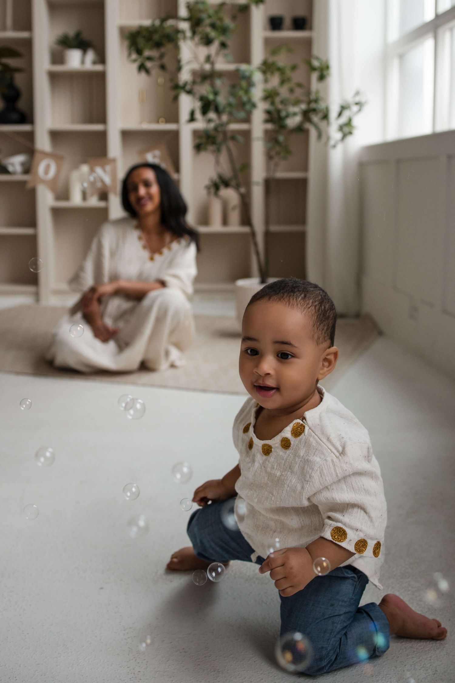 One-year-old exploring bubbles during a cake smash session at Mint Room Studios in Toronto with timeless neutral styling and decor.