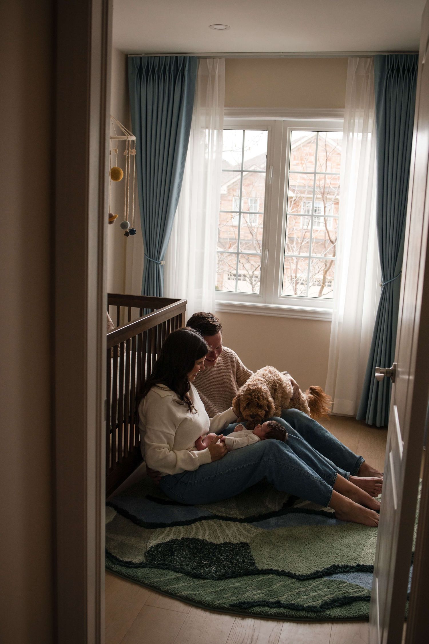 Parents, newborn, and family dog sharing a peaceful moment in the nursery during a Toronto newborn session.