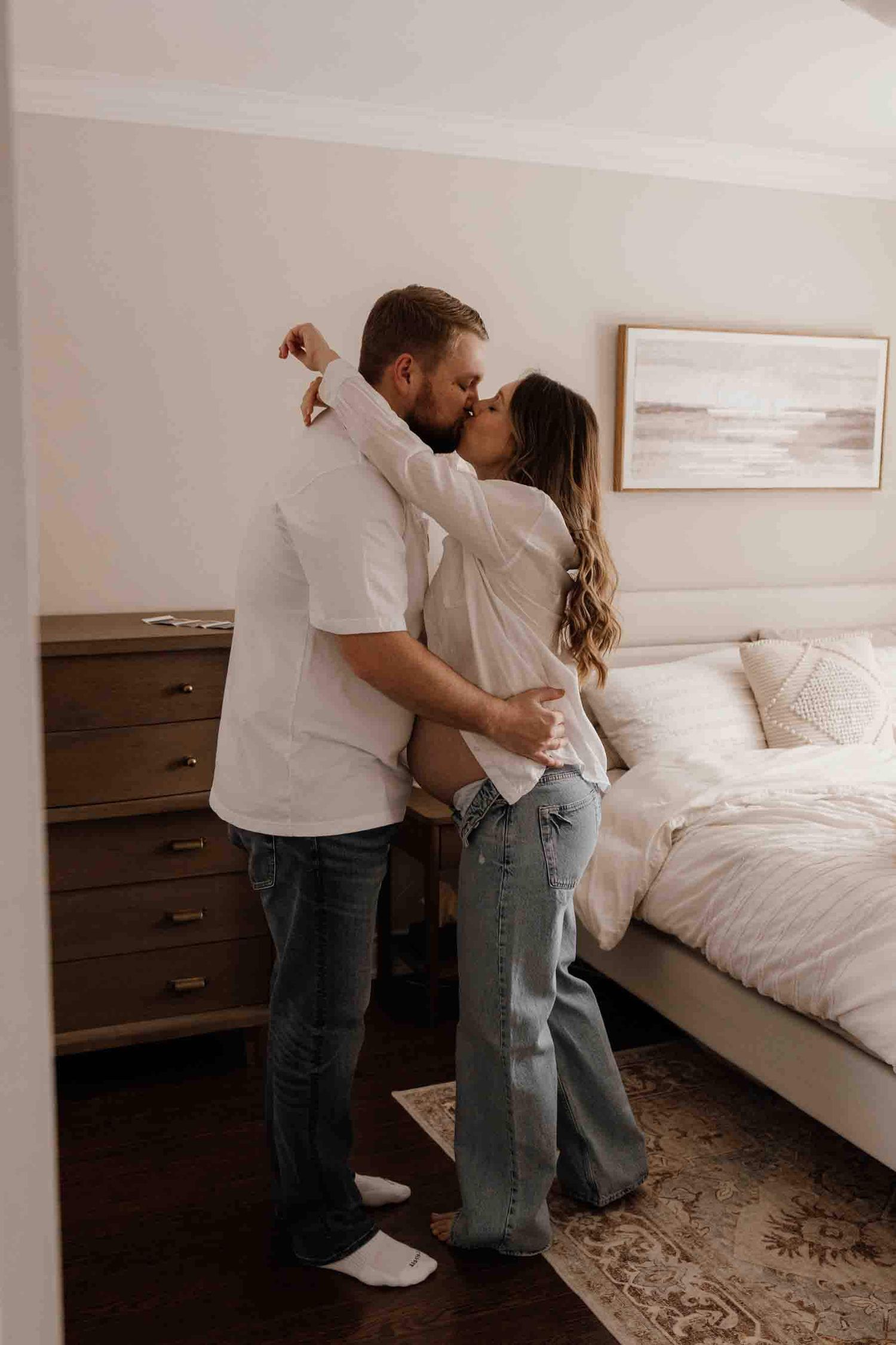 Expectant parents sharing a tender kiss during an in-home maternity photography session in Toronto, celebrating anticipation.
