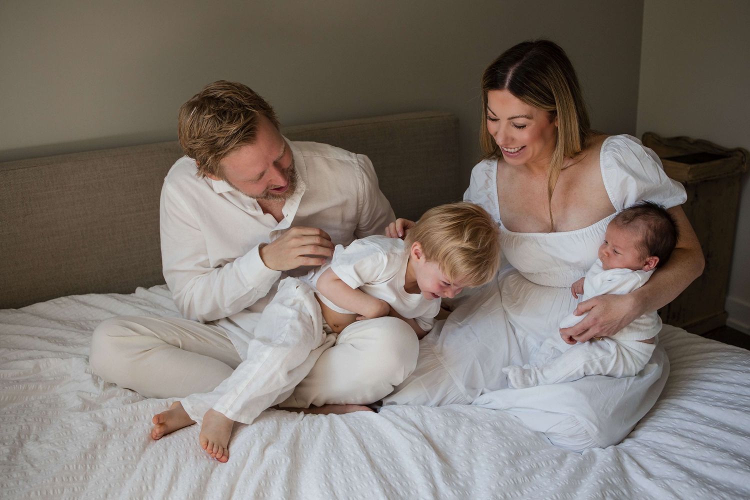 Family of four sharing a joyful moment during an in-home lifestyle newborn photography session in Toronto.
