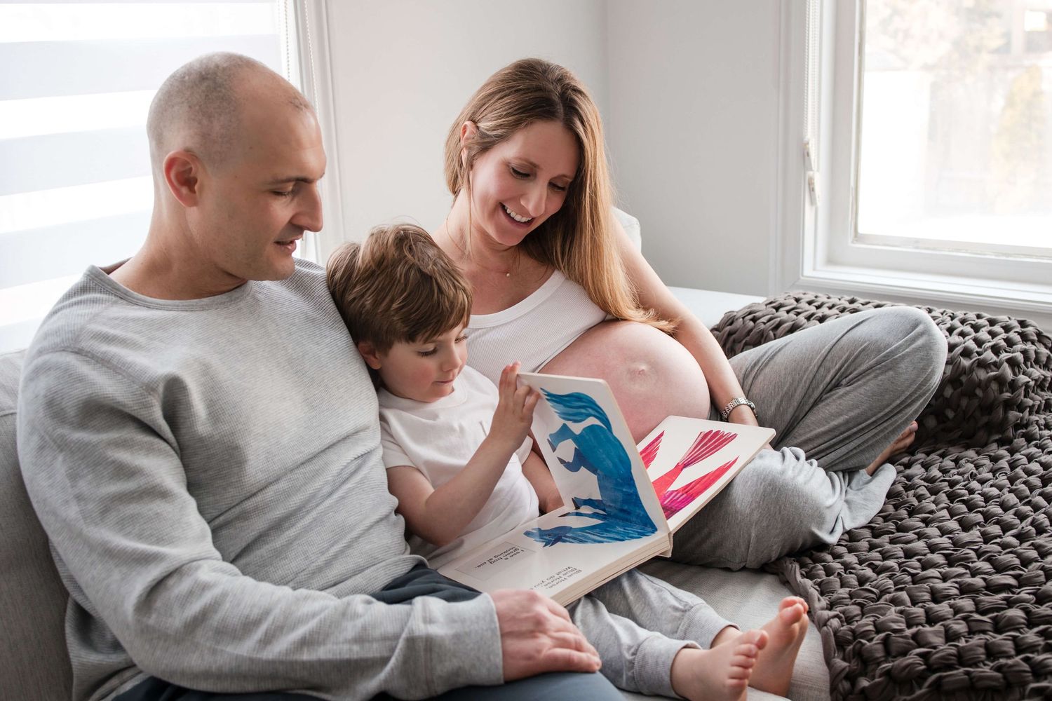 Expectant parents reading with their child during an in-home maternity photography session in Toronto, celebrating a growing family.
