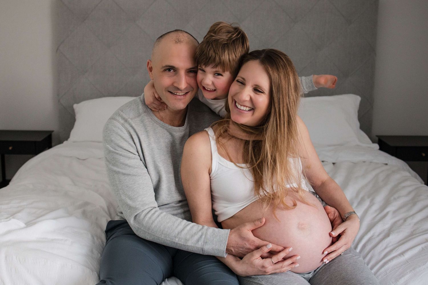Expectant parents and their child sharing a joyful family moment during an in-home maternity photography session in Toronto.