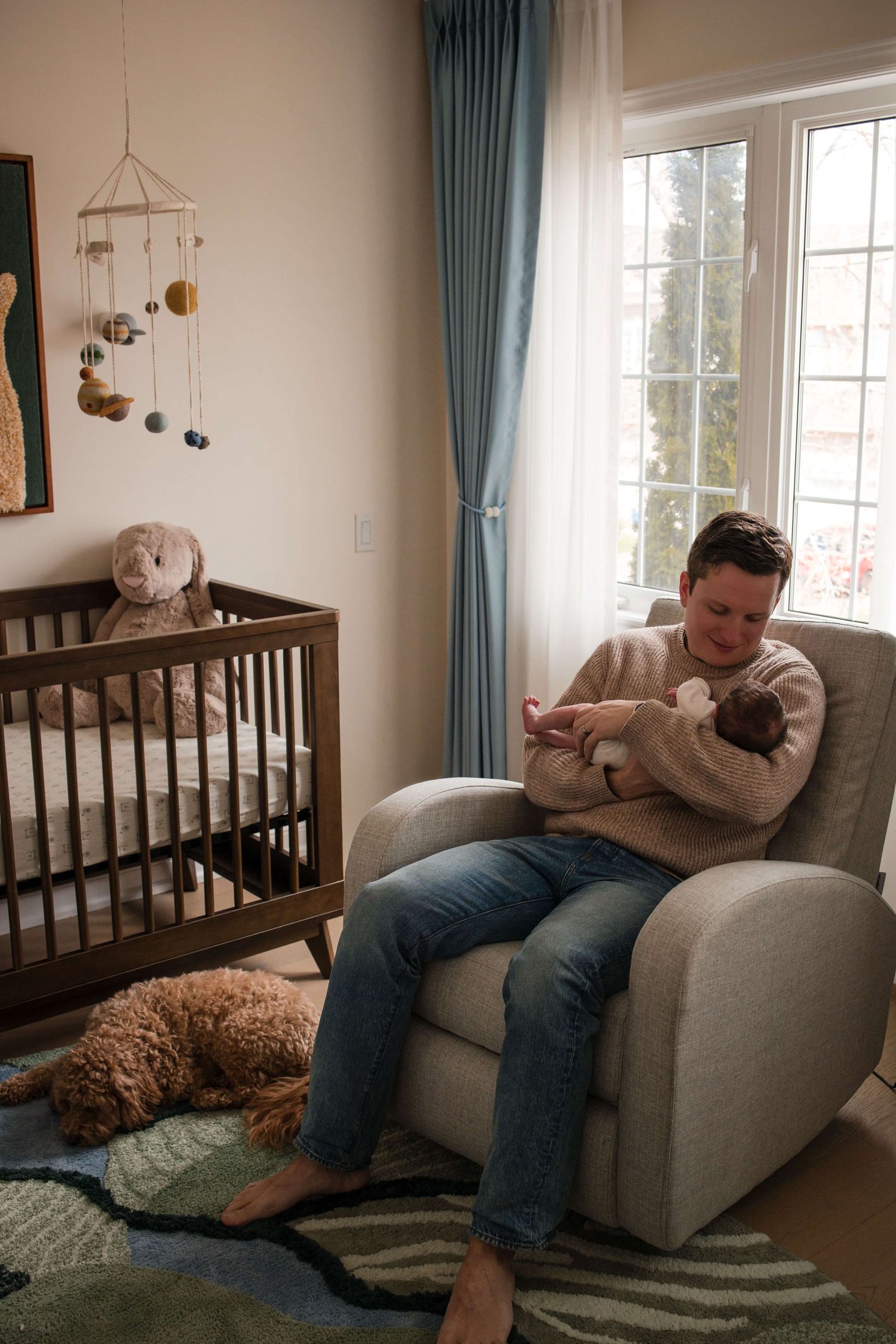 Dad holding his newborn in the nursery during a lifestyle newborn photography session in Toronto.