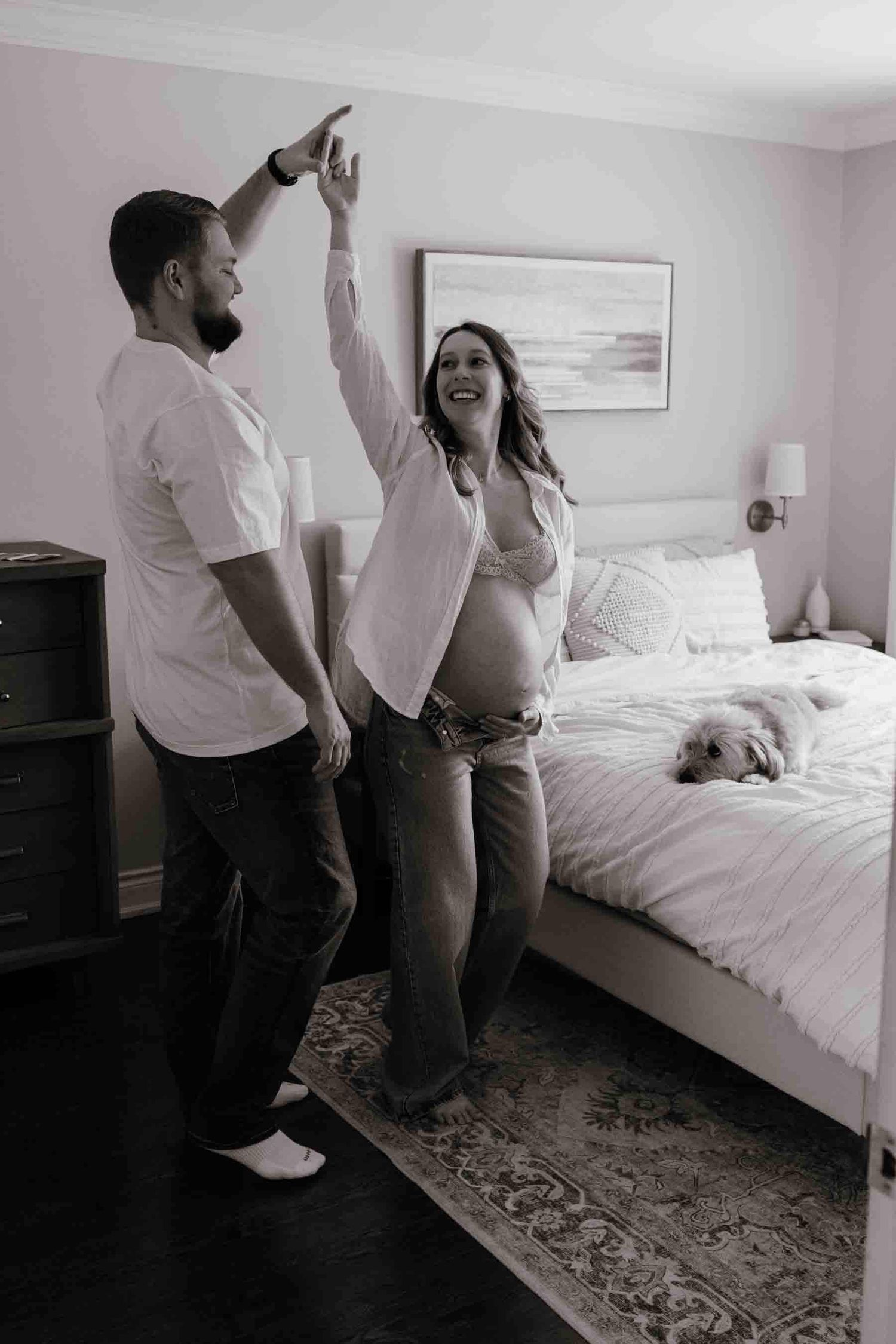 Expectant parents sharing a playful dance during an in-home maternity photography session in Toronto, celebrating anticipation.
