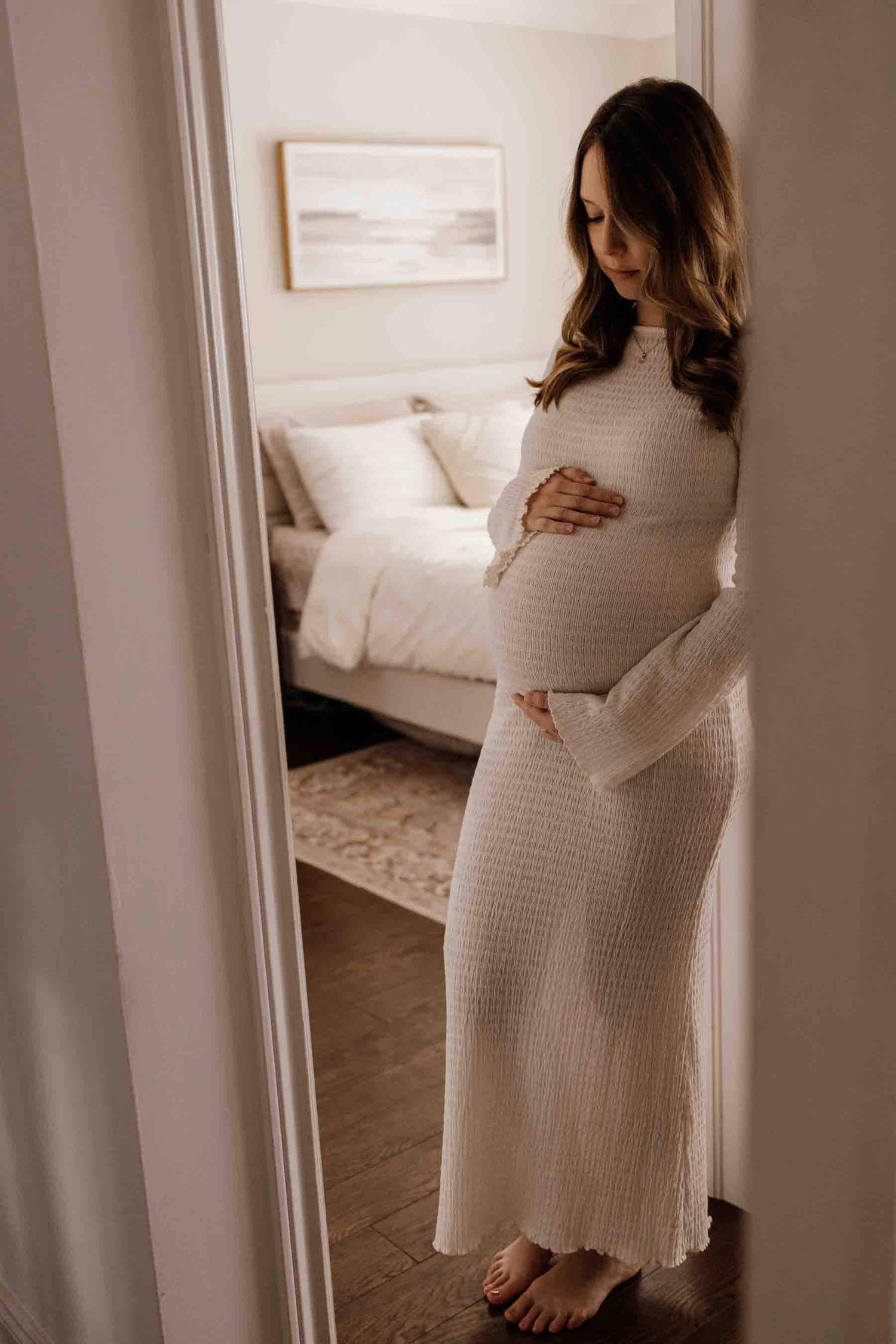 Expectant mother embracing her baby bump during an in-home maternity photography session in Toronto, capturing motherhood and anticipation.