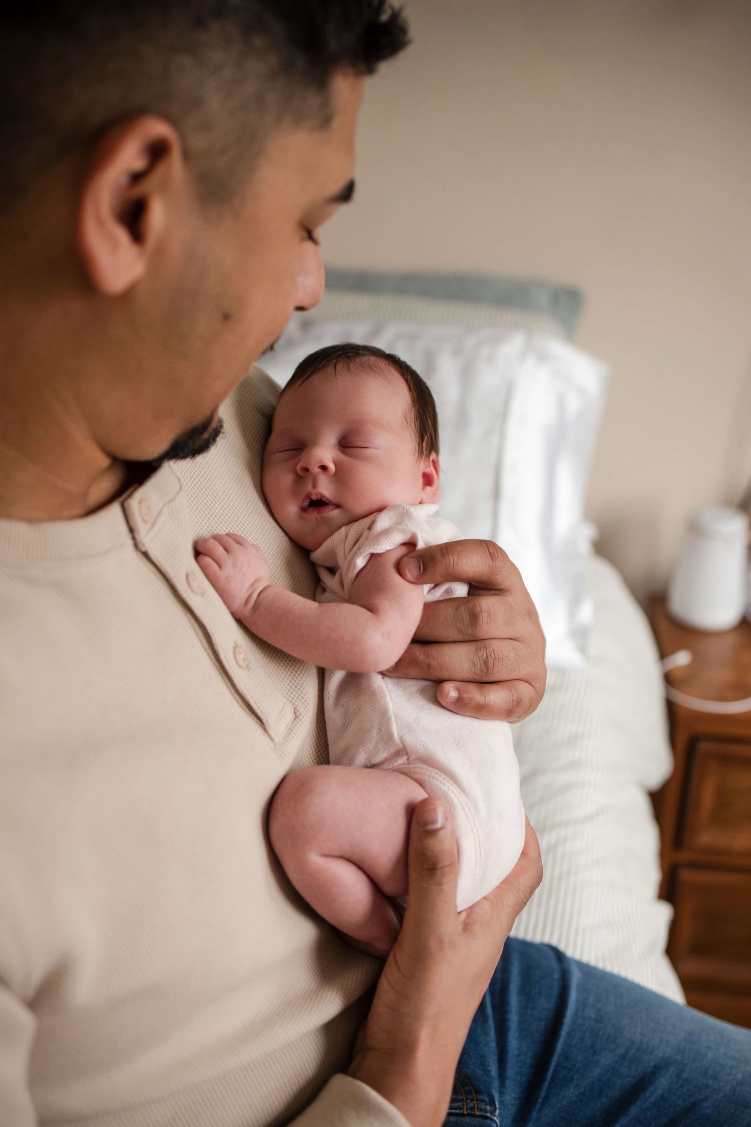 Father holding his sleeping newborn during an in-home newborn photography session in Toronto, capturing love, comfort, and connection.