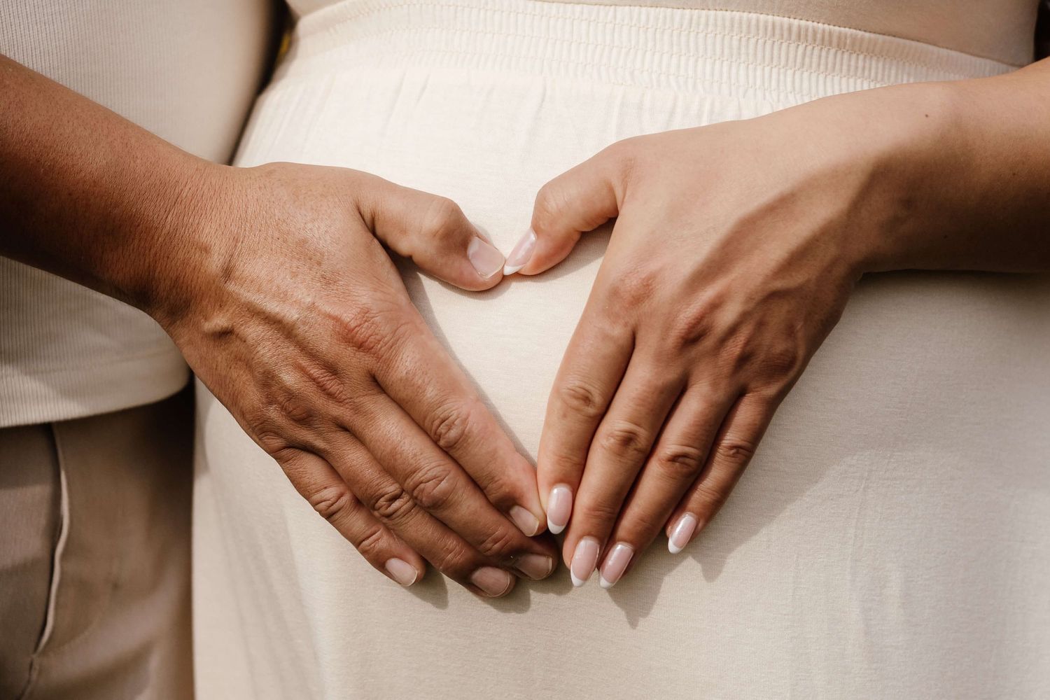 Close-up of expectant parents’ hands forming a heart over a baby bump during a maternity photography session in Toronto.
