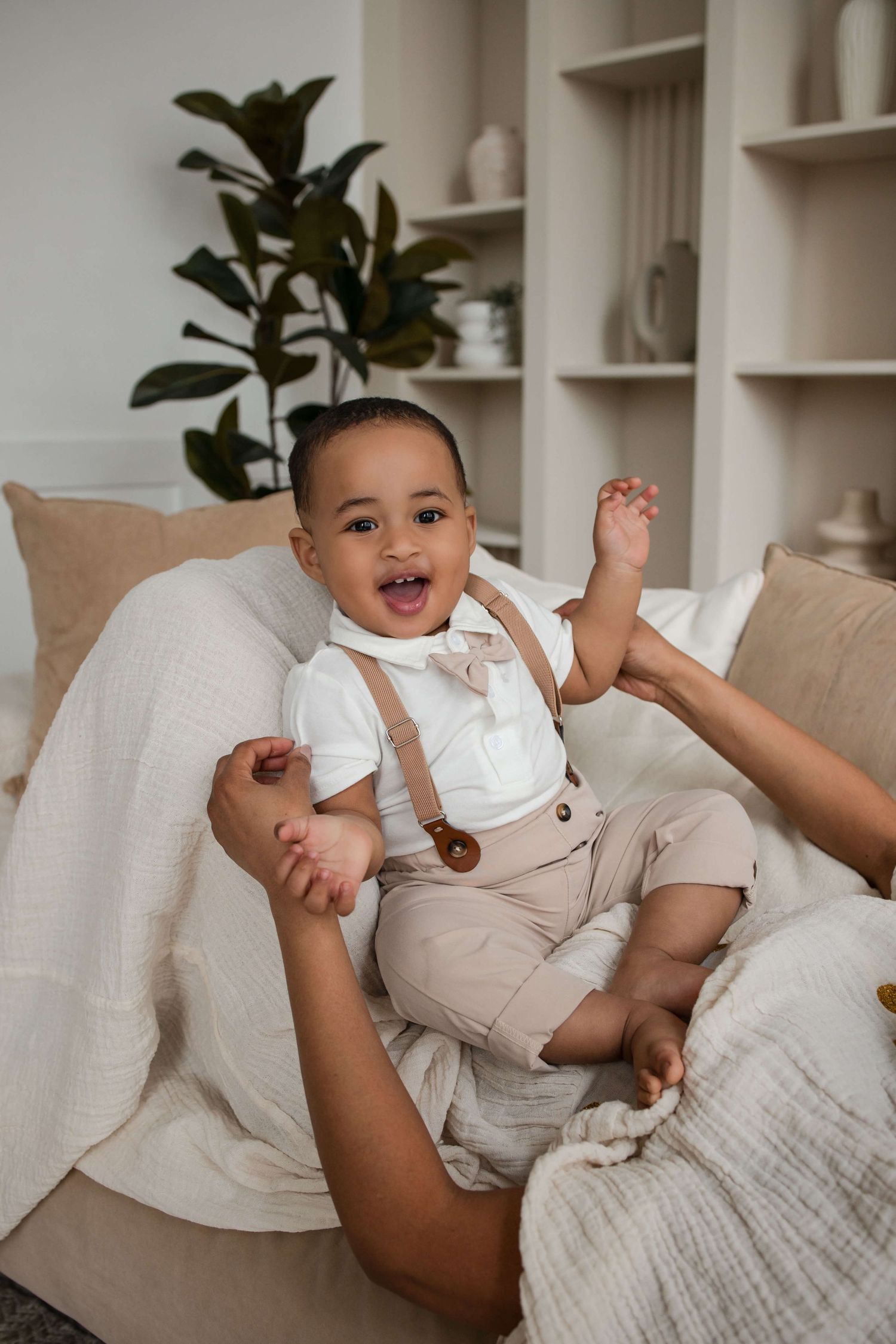 Smiling one-year-old cuddled by a parent during a cake smash session at Mint Room Studios in Toronto with timeless neutral styling.
