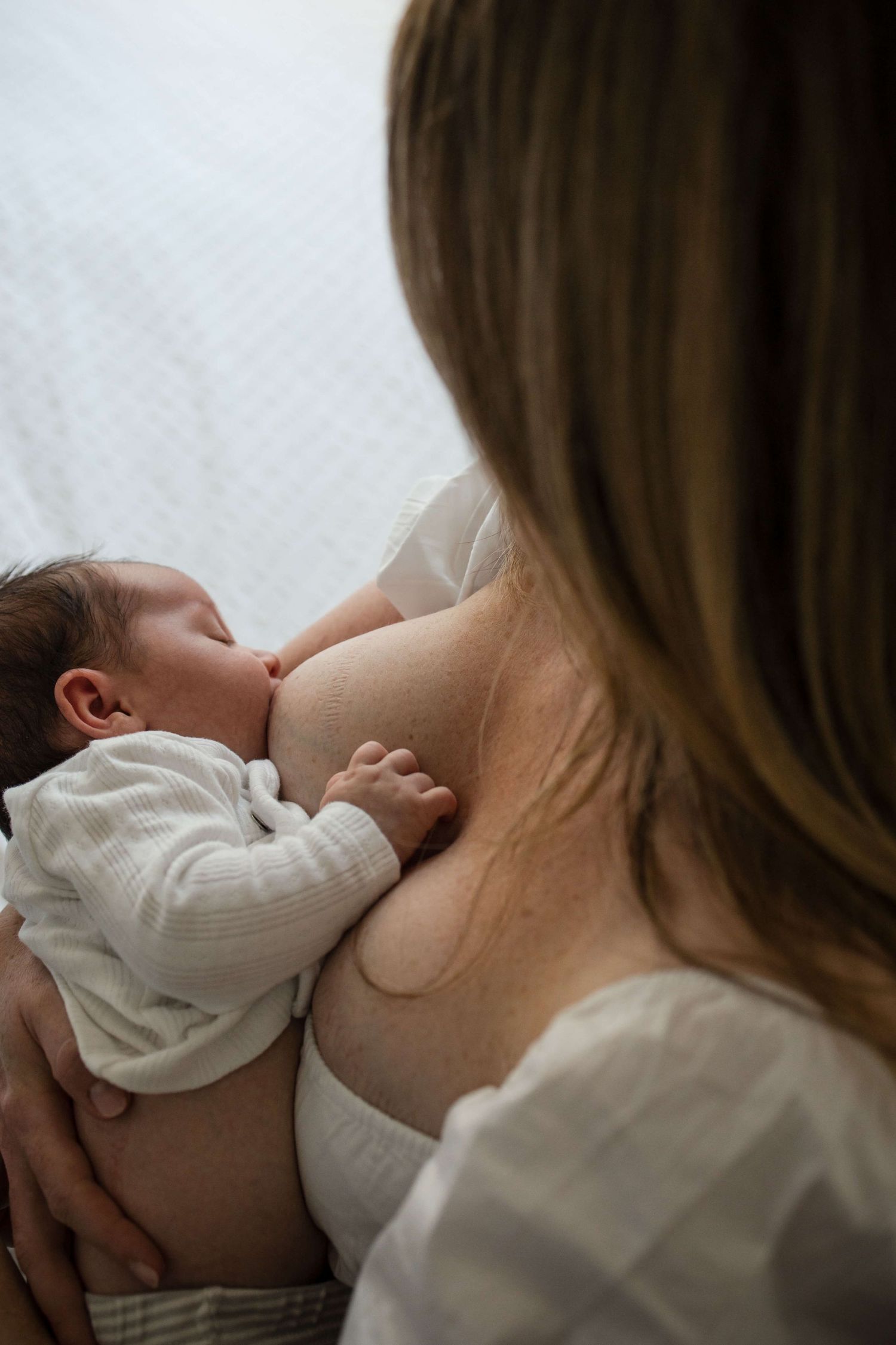 Breastfeeding mother and newborn sharing a quiet bonding moment at home in Toronto.