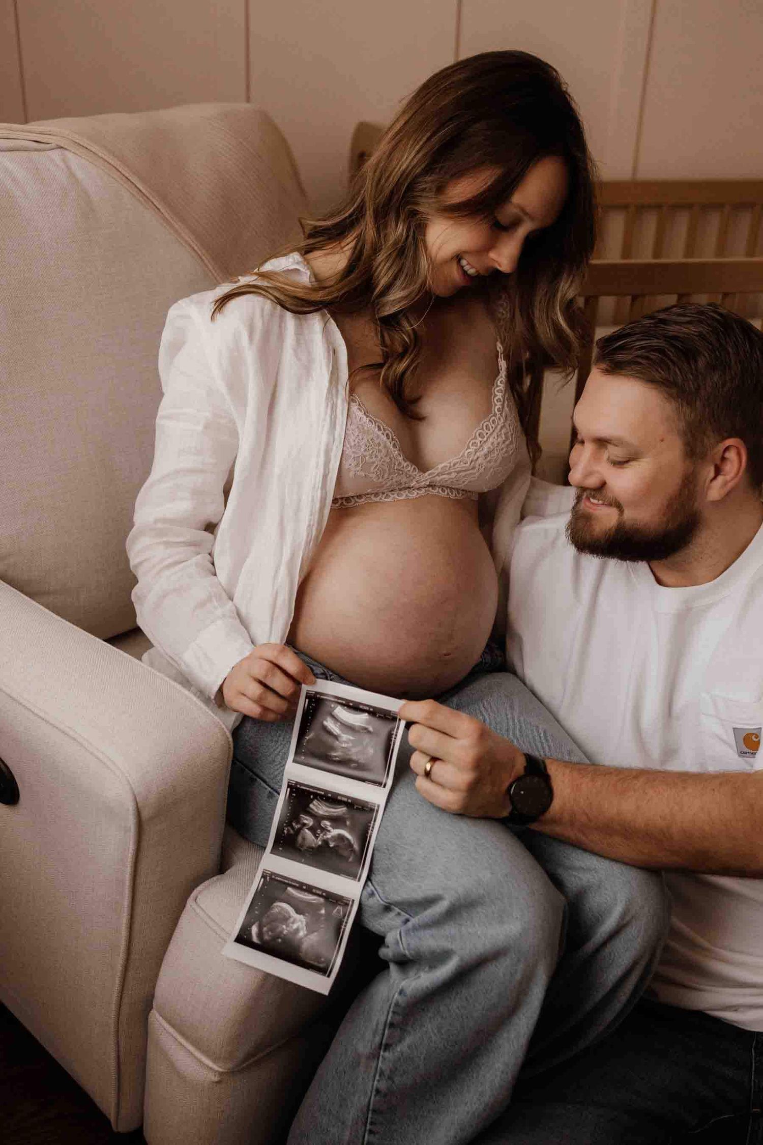 Expectant parents admiring ultrasound photos during an in-home maternity photography session in Toronto, celebrating anticipation.