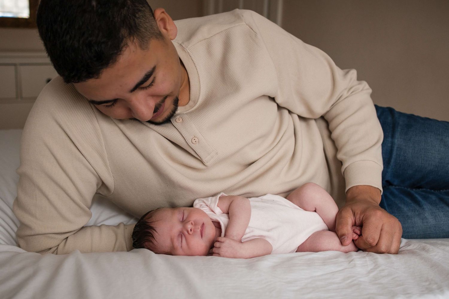 Father gazing at his newborn during an in-home newborn photography session in Toronto, capturing love, connection, and family.