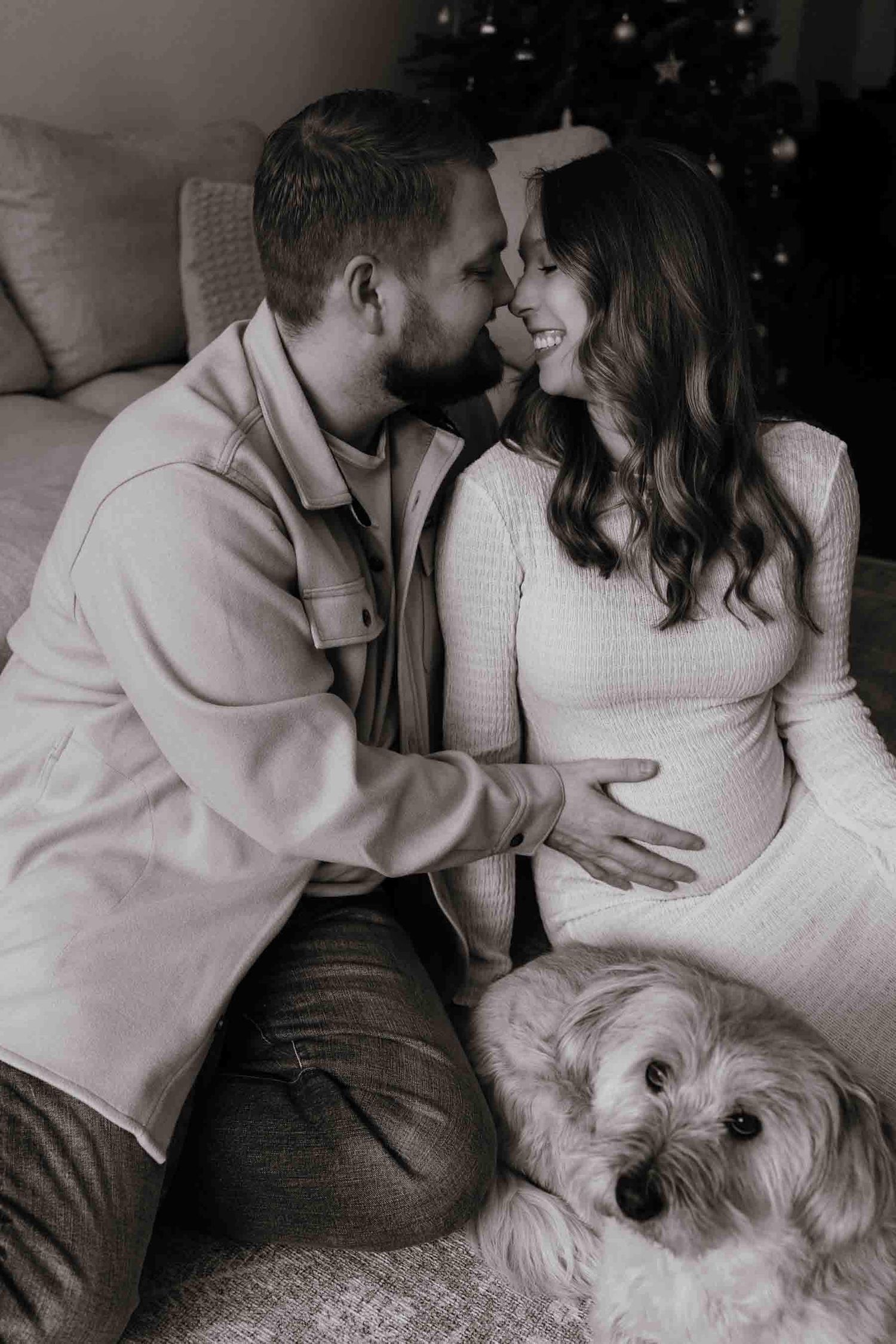 Expectant parents sharing a tender moment with their dog during an in-home maternity photography session in Toronto, celebrating family.
