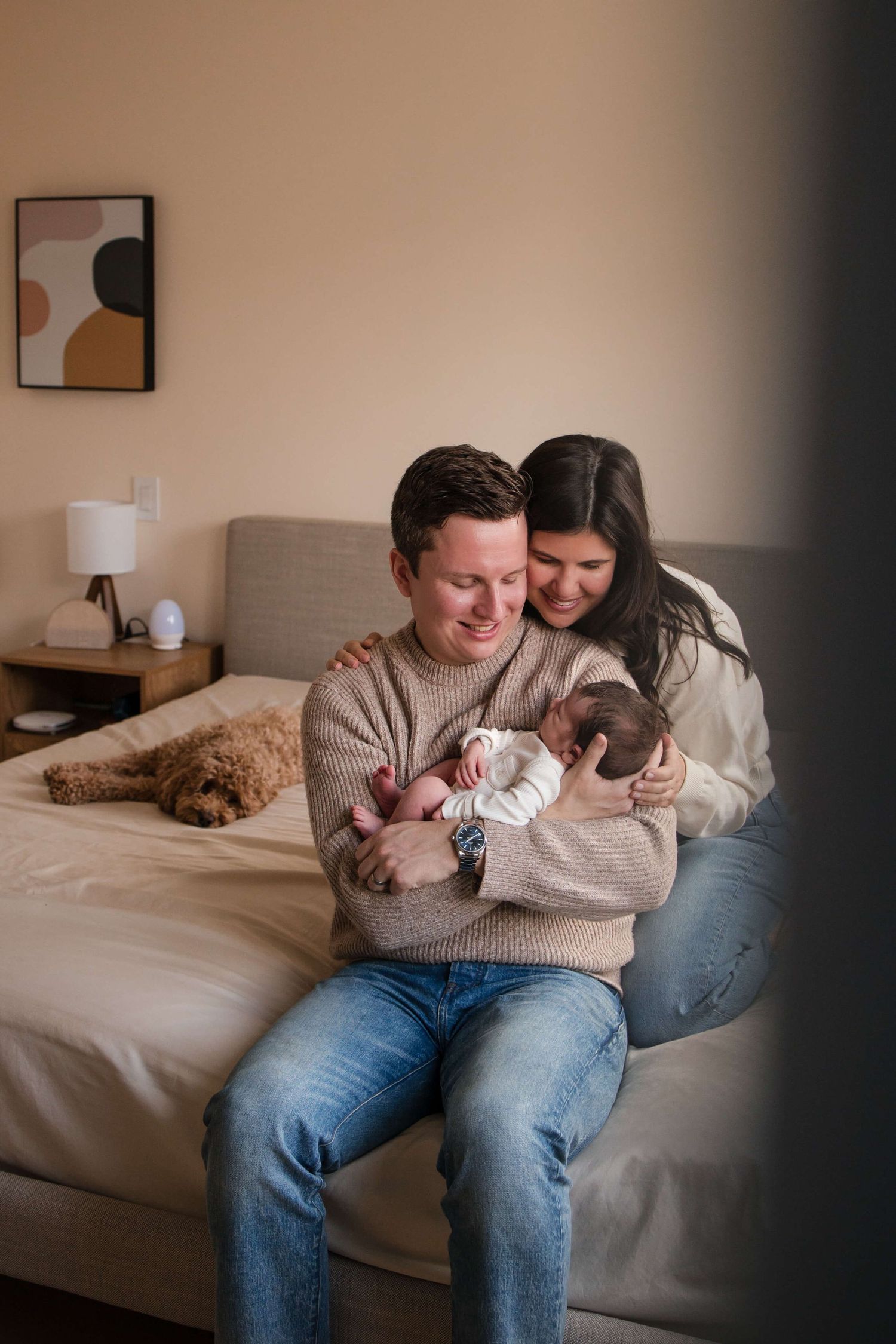 New parents bonding with their newborn and family dog during an in-home newborn session in Toronto.