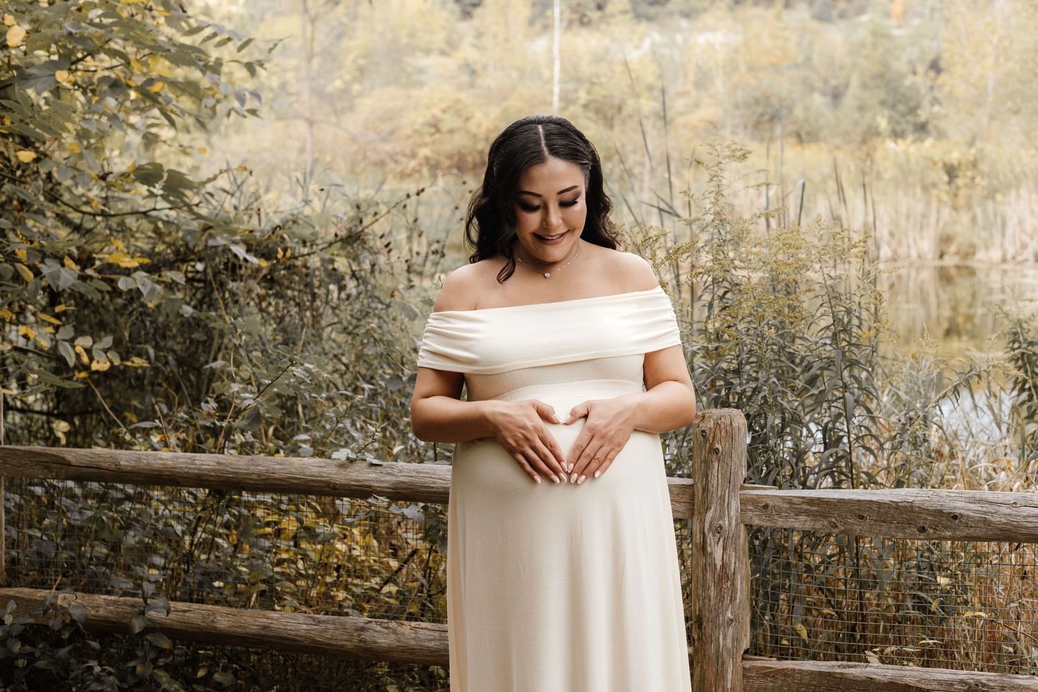 Expectant mother embracing her growing baby bump at Evergreen Brick Works during an outdoor maternity photography session in Toronto.