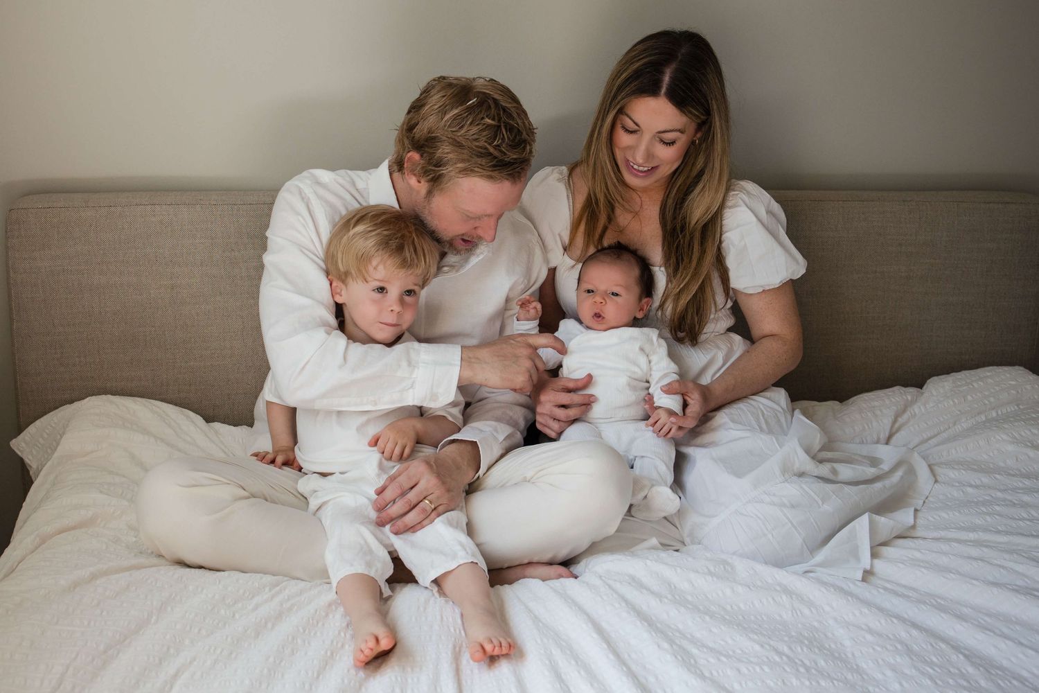 Family of four sharing a tender moment during an in-home newborn photography session in Toronto.