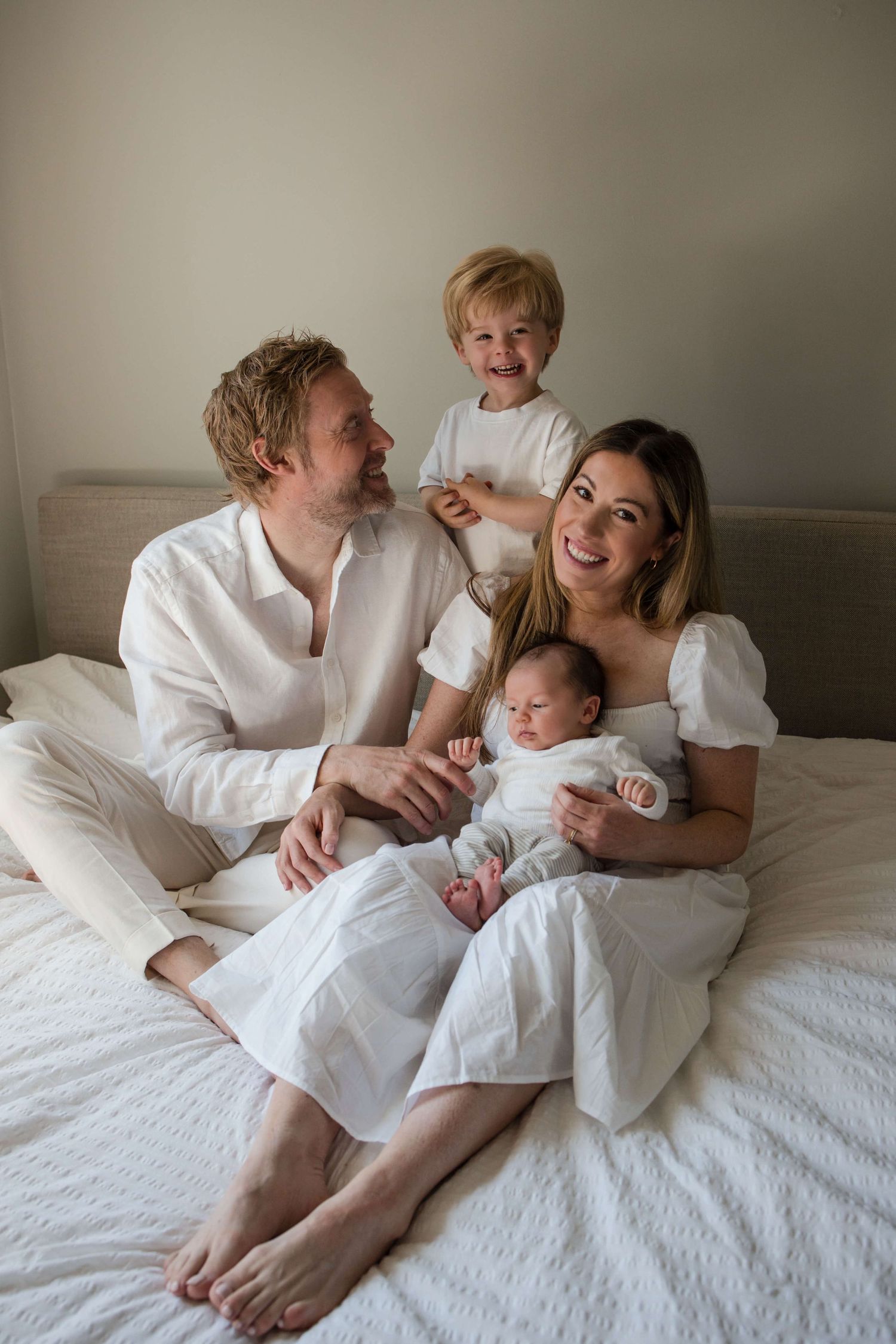 Parents, toddler, and newborn sharing a happy moment during a lifestyle newborn session in Toronto.