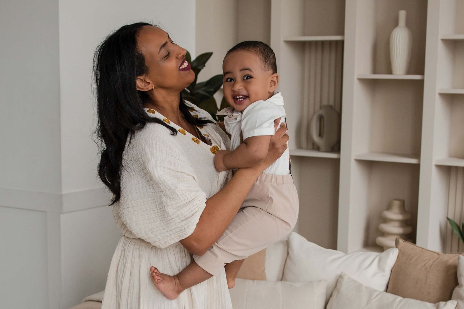 Mother holding her smiling baby during a lifestyle family session at Mint Room Studios in Toronto with timeless neutral styling.