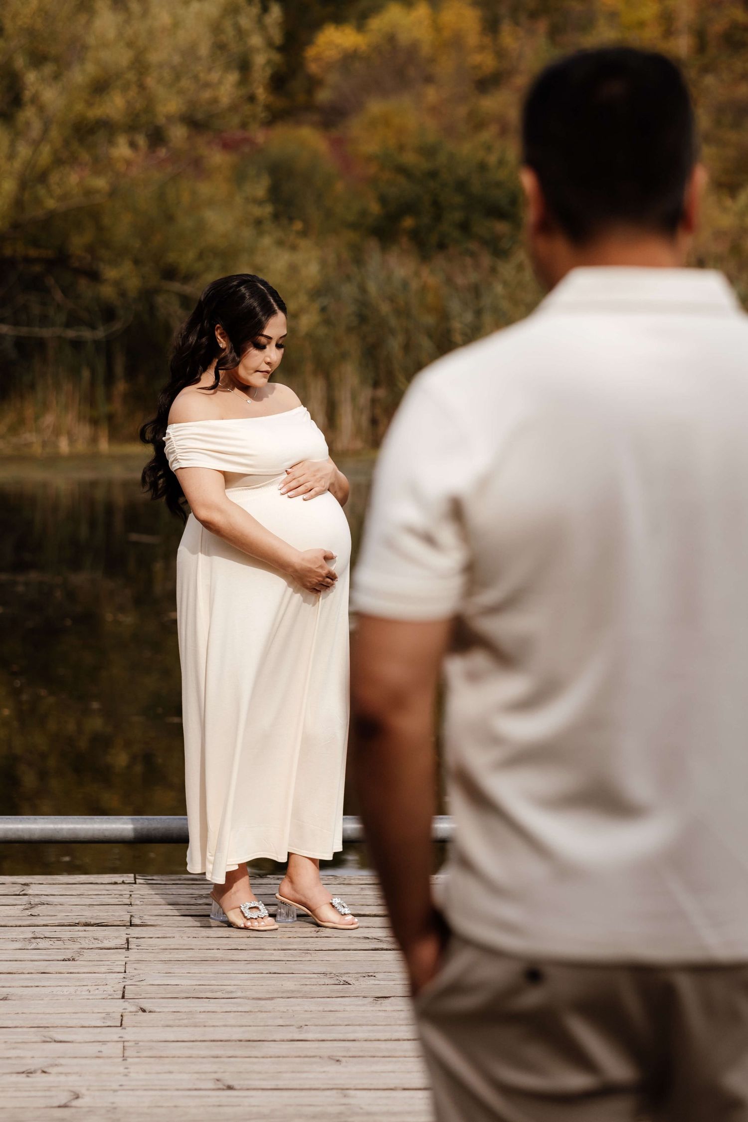 Expectant mother embracing her growing baby bump at Evergreen Brick Works during an outdoor maternity photography session in Toronto.