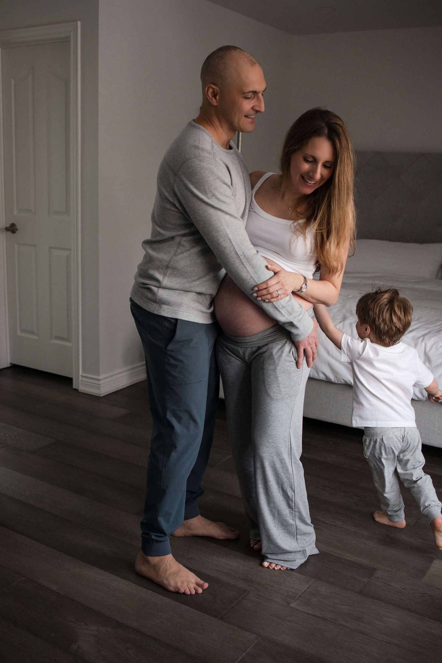 Expectant parents sharing a quiet moment with their toddler during an in-home maternity photography session in Toronto, celebrating family.