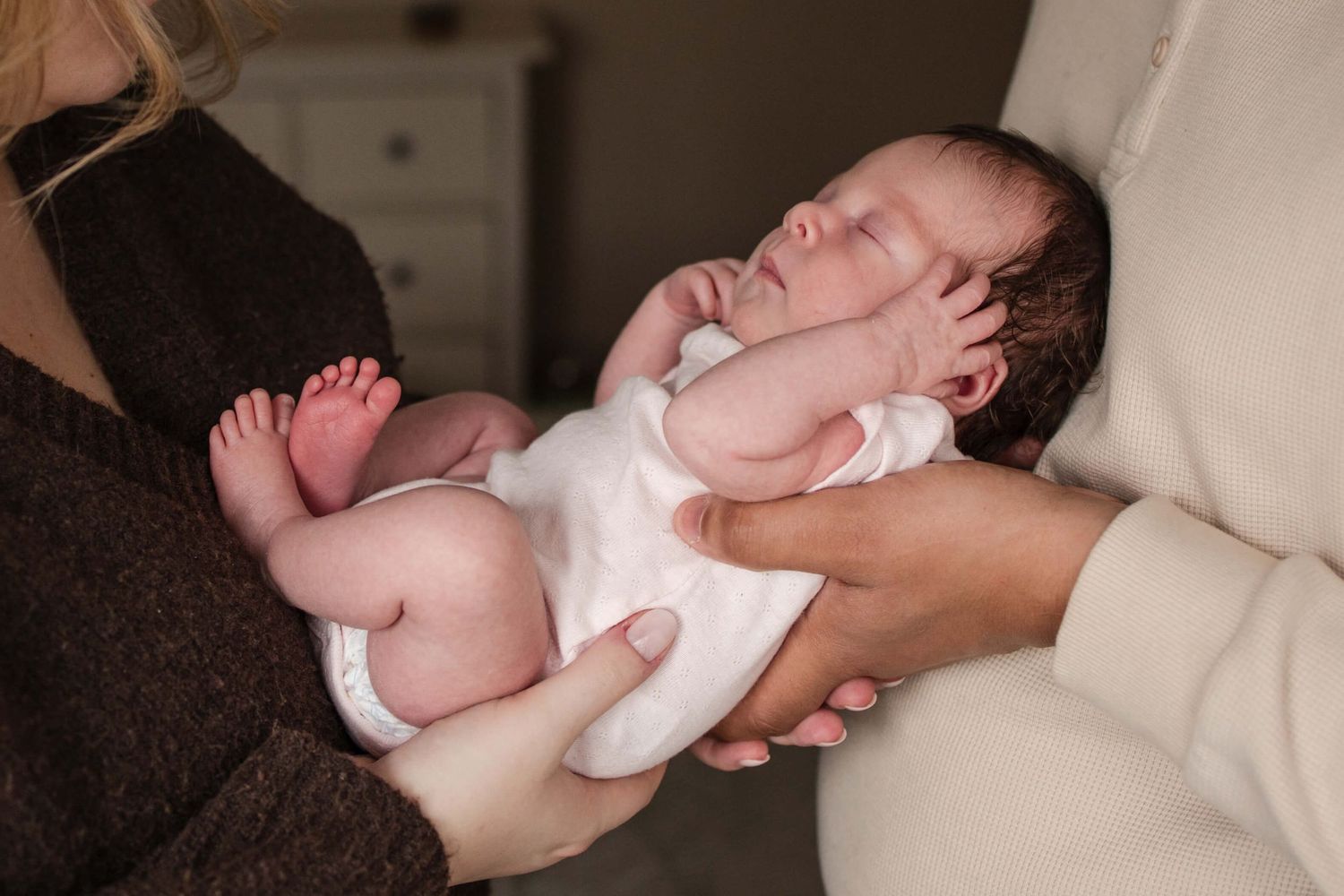 Newborn cradled in loving parents’ hands during an in-home newborn photography session in Toronto, capturing warmth and connection.