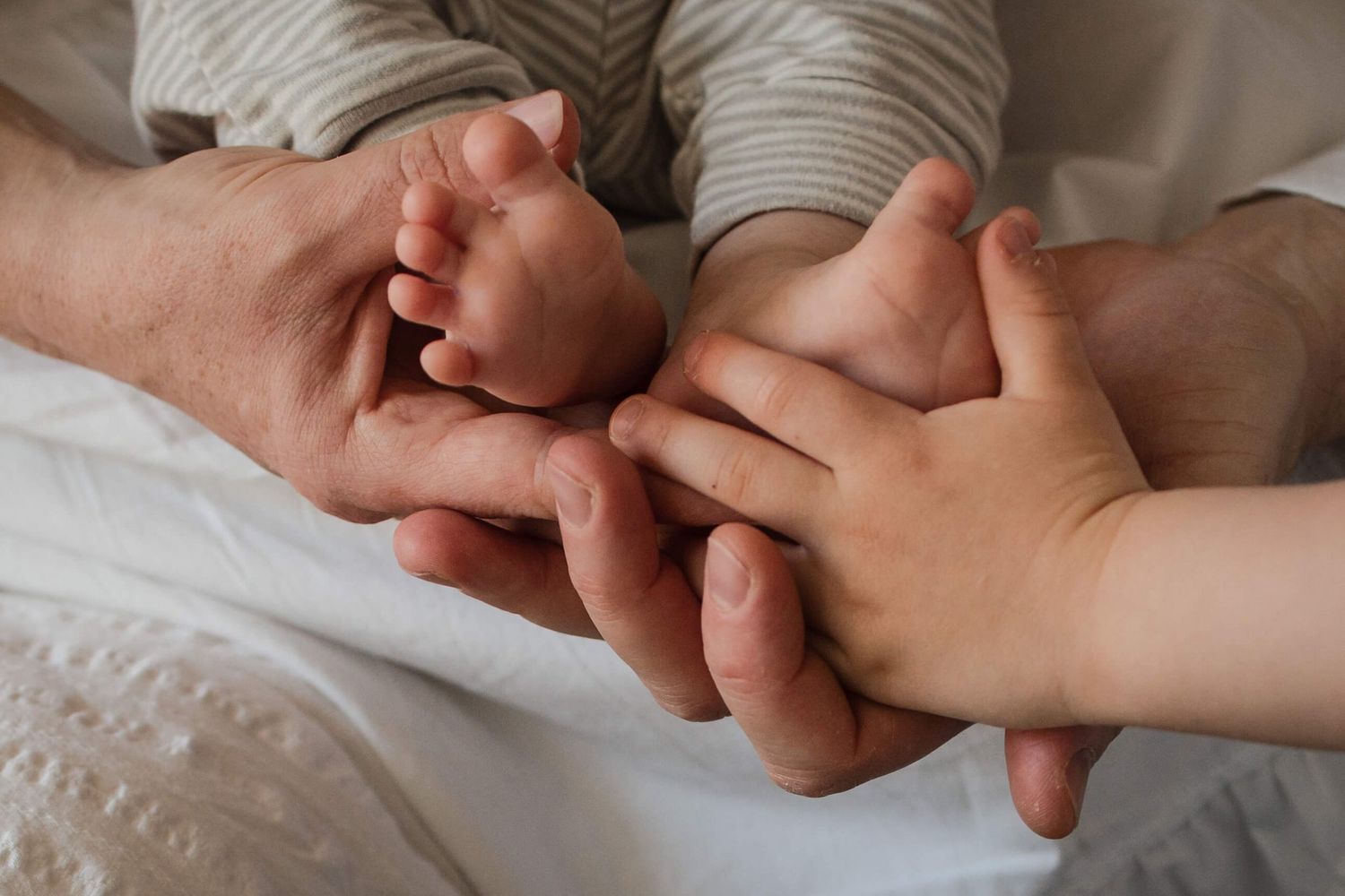Big sibling touching newborn's tiny feet during a lifestyle newborn photography session in Toronto.