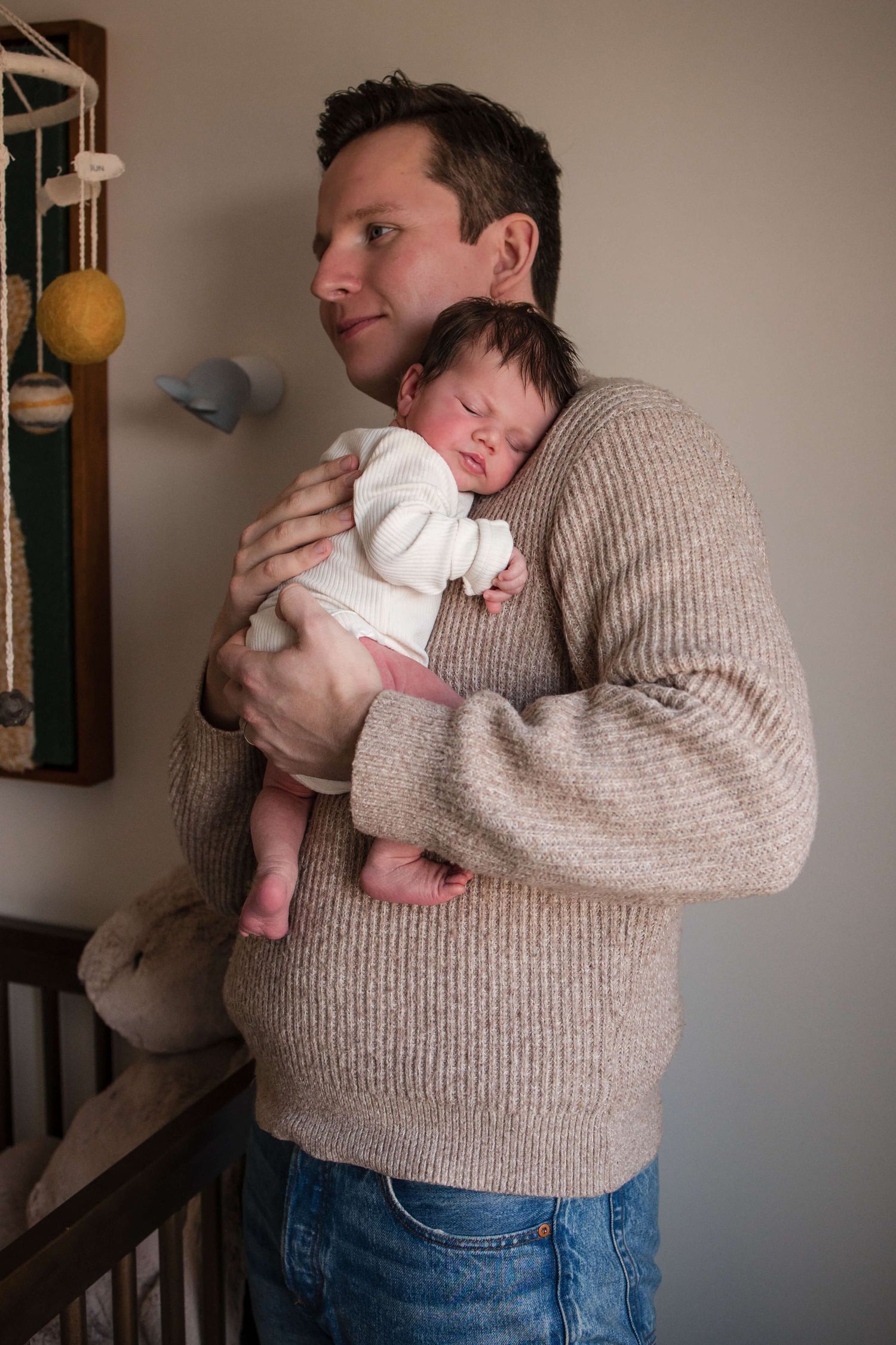 Dad holding his newborn in the nursery during a lifestyle newborn photography session in Toronto.