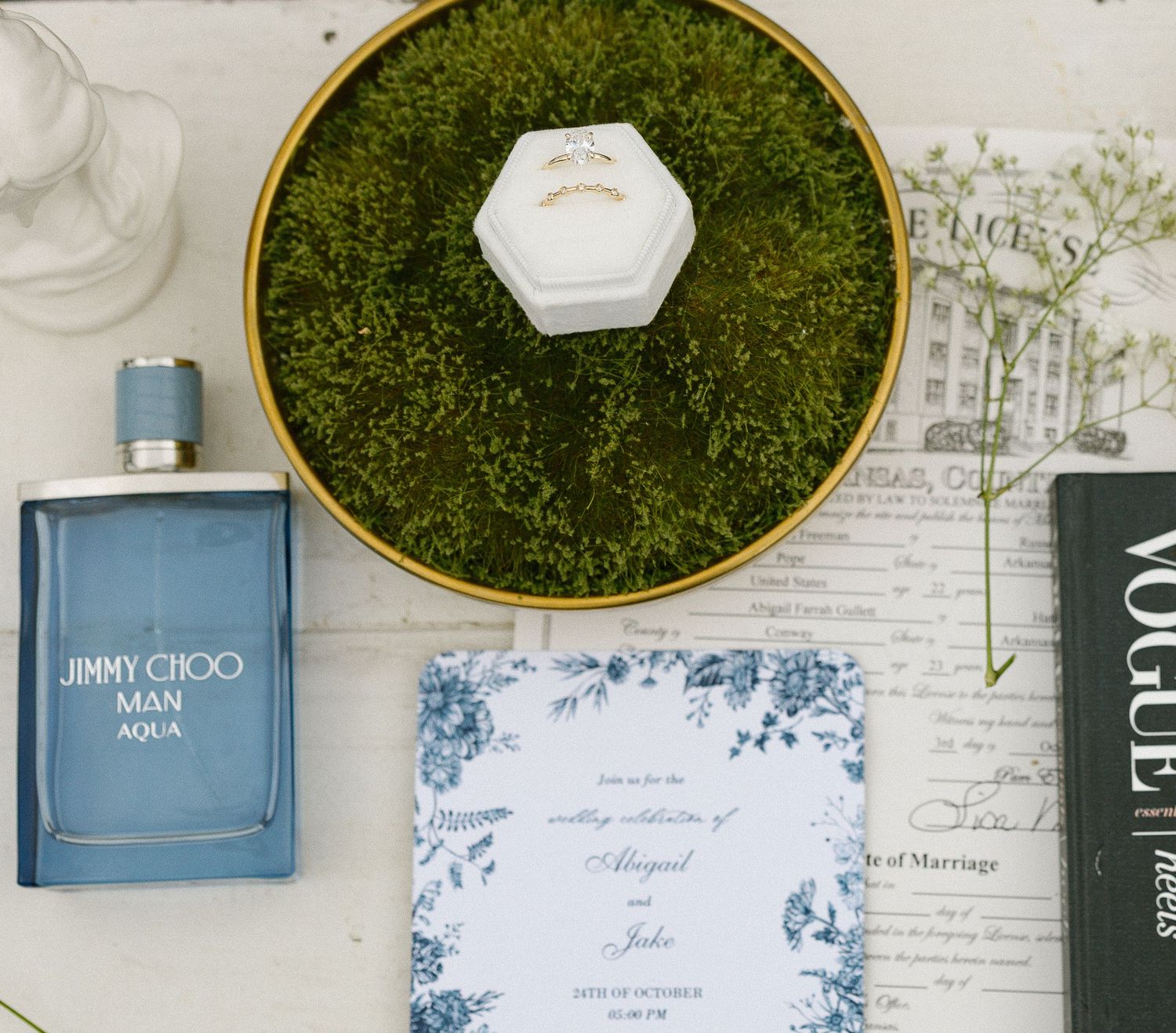 Wedding invitation display with moss wall decor and elegant typography.