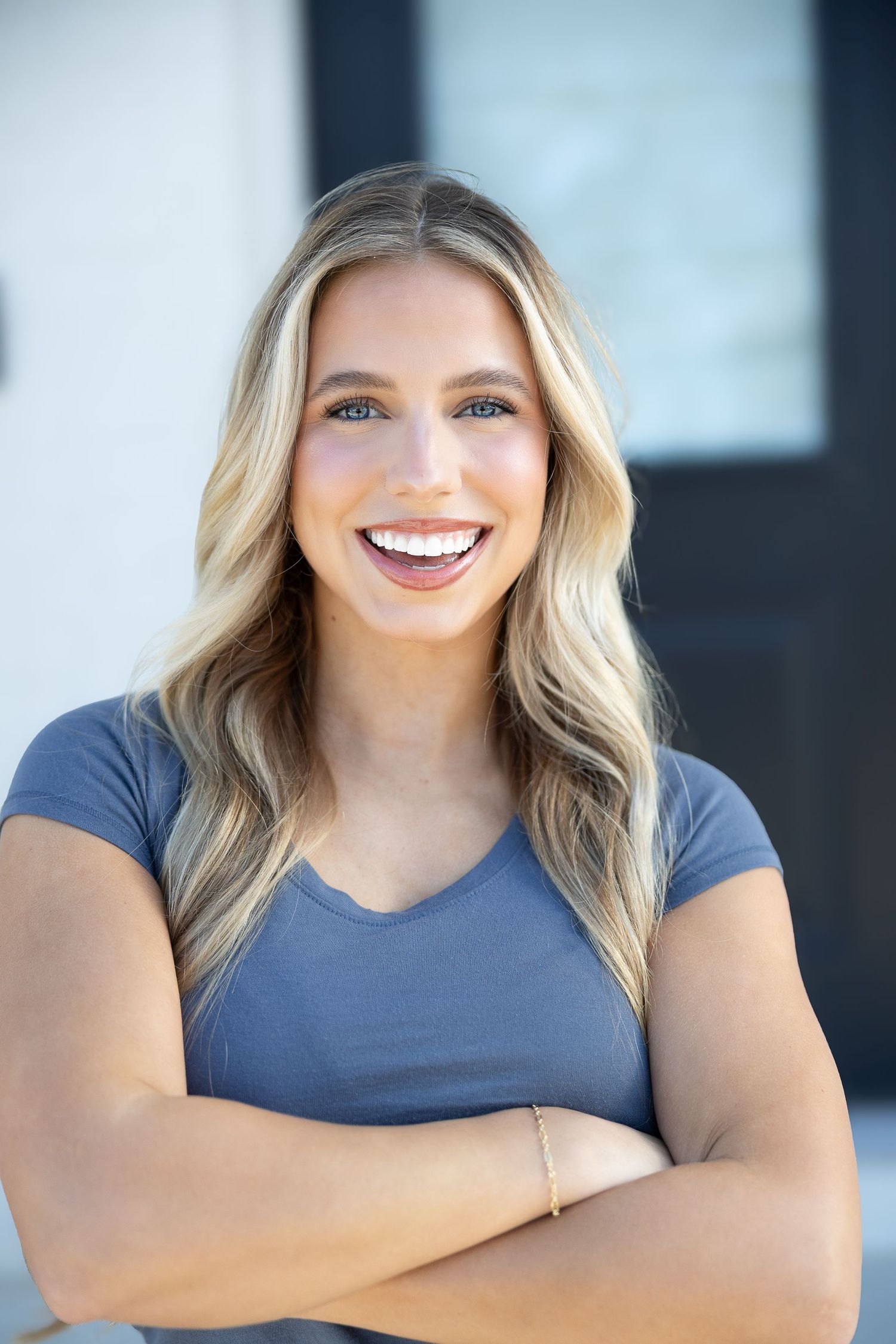 Professional headshot series showing bright smile and casual blue top against dark background.