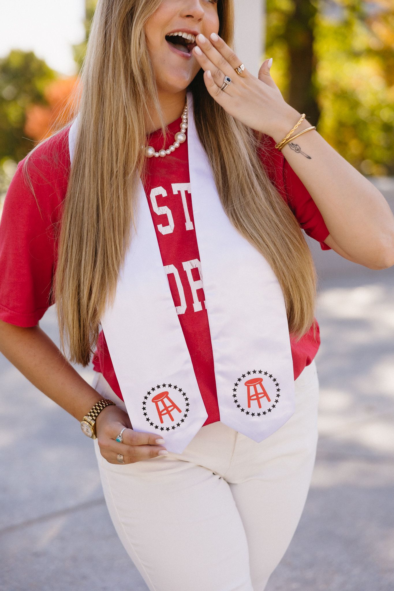 A red and white varsity-style scarf with embroidered circular designs is displayed in multiple styled photos outdoors.