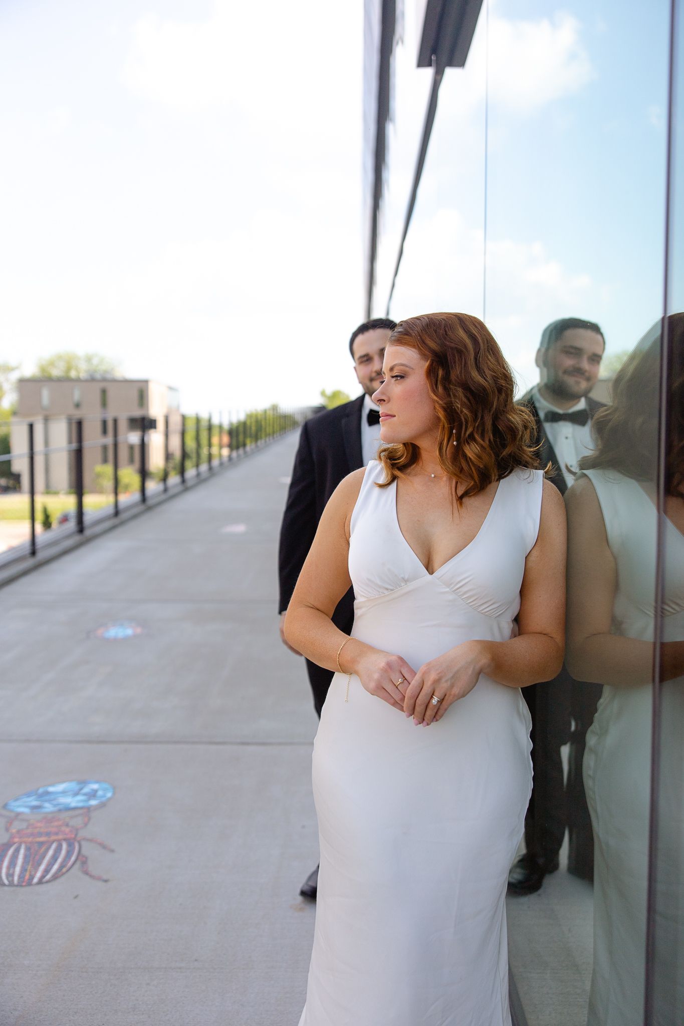 Wedding photos showing a person in white dress posing against reflective glass windows.