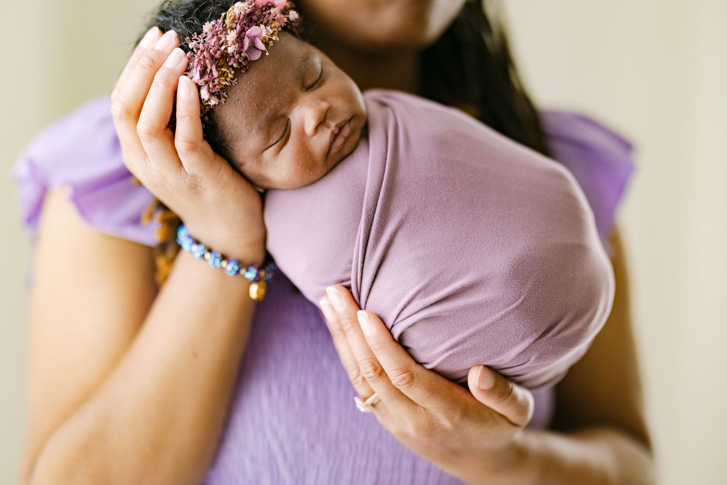 Woman in lavender top holds a pink scrunchie while posing against a light background.