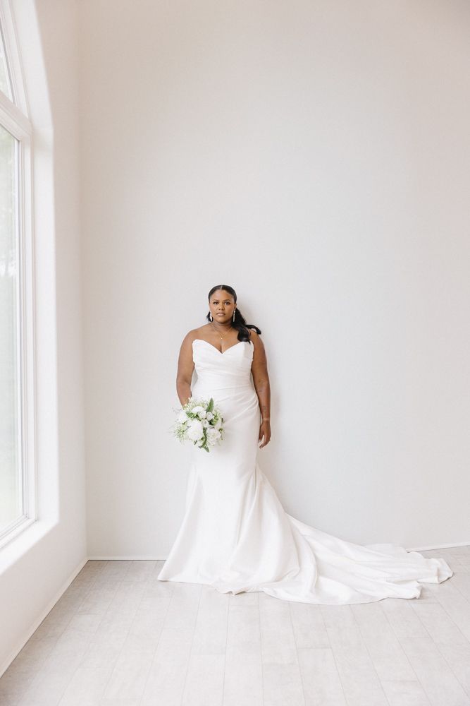 Classic white wedding dress with long train photographed in minimalist studio setting.