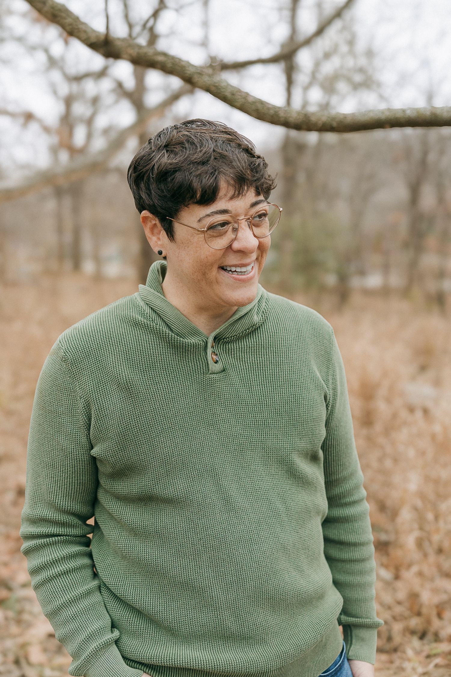 Person in green sweater sitting outdoors during autumn photoshoot.