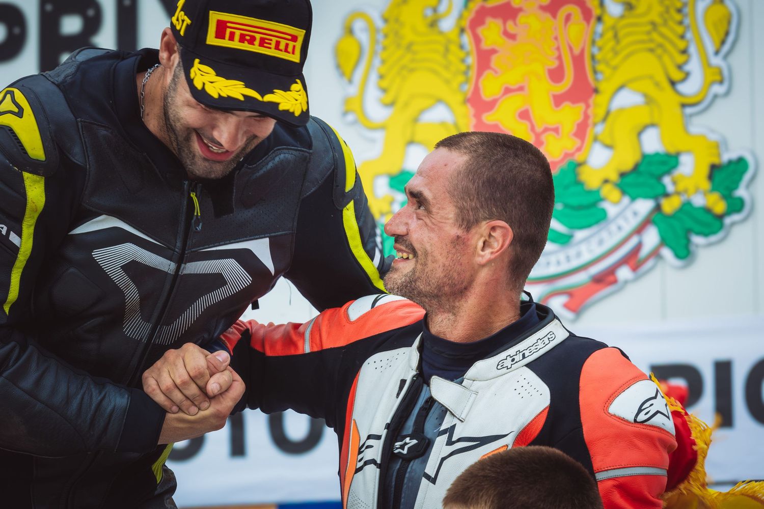 Motorcycle racers shaking hands during podium celebration after race – sports photography in Bulgaria.