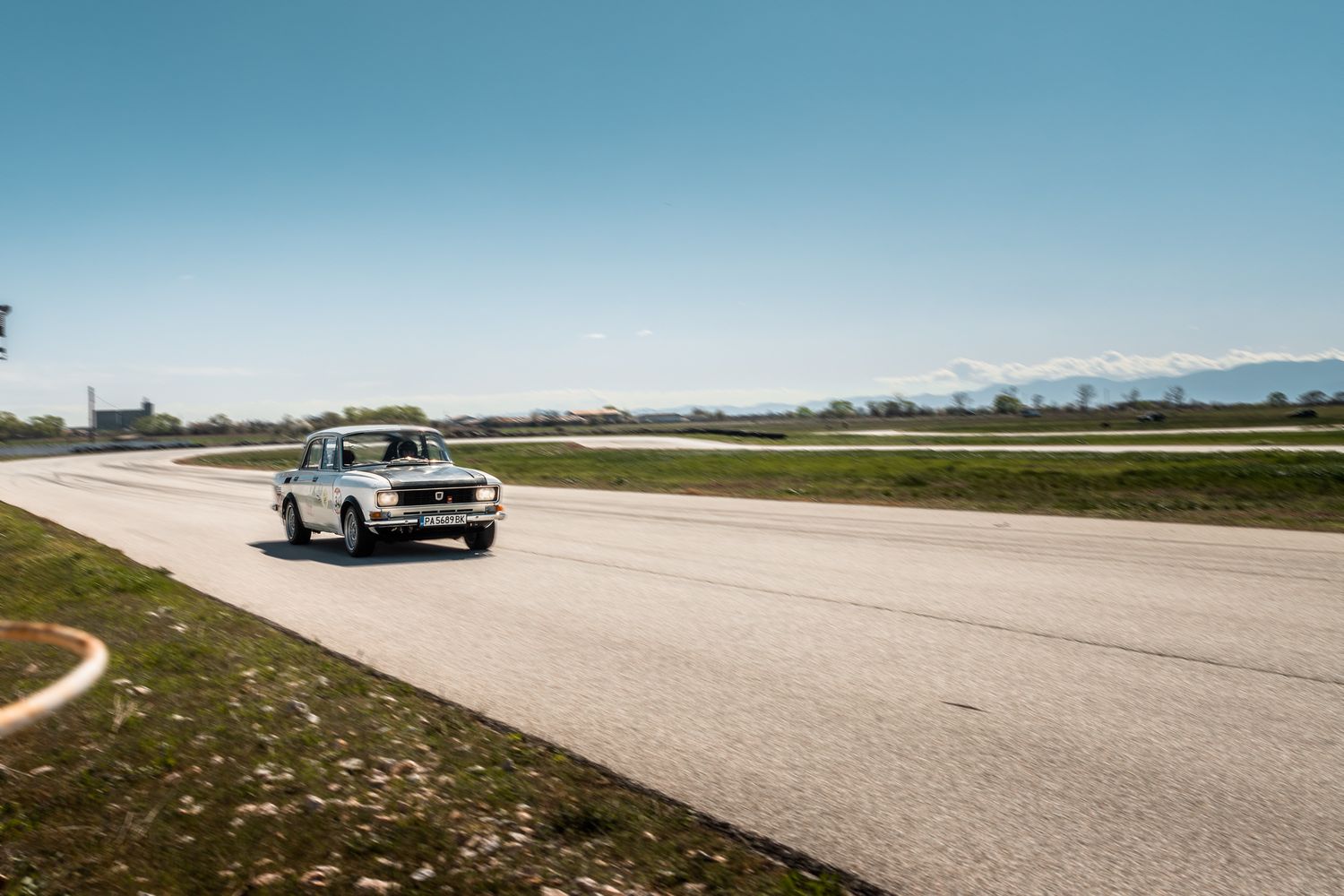 Classic car accelerating on track during a motorsport event in Bulgaria, capturing speed, space and open horizon atmosphere.