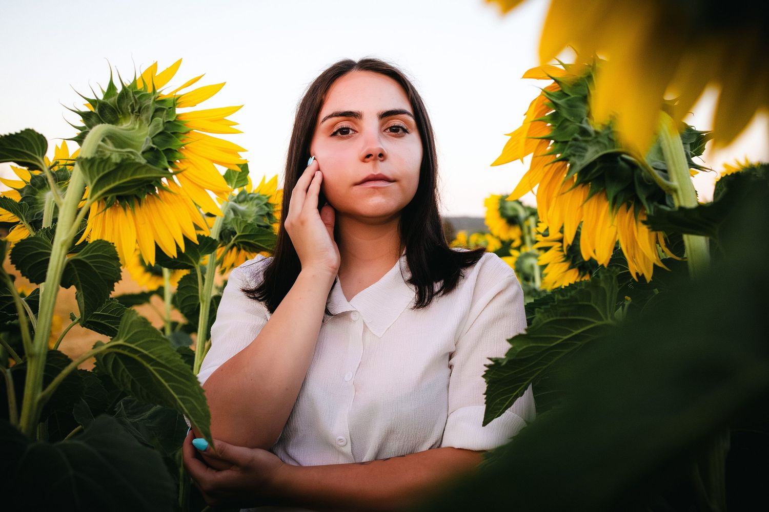Natural light portrait of a woman standing among sunflowers at golden hour – outdoor portrait photography. in Bulgaria